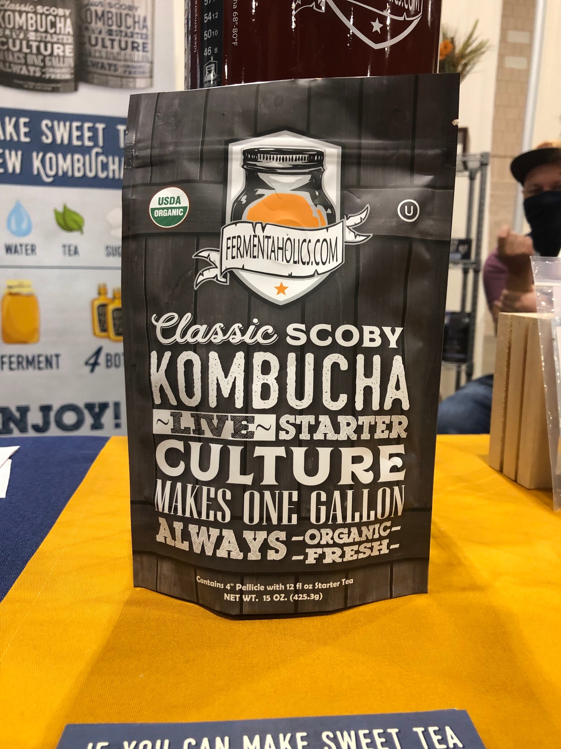 A black Fermentaholics Classic SCOBY Kombucha live starter culture pouch on a yellow tablecloth