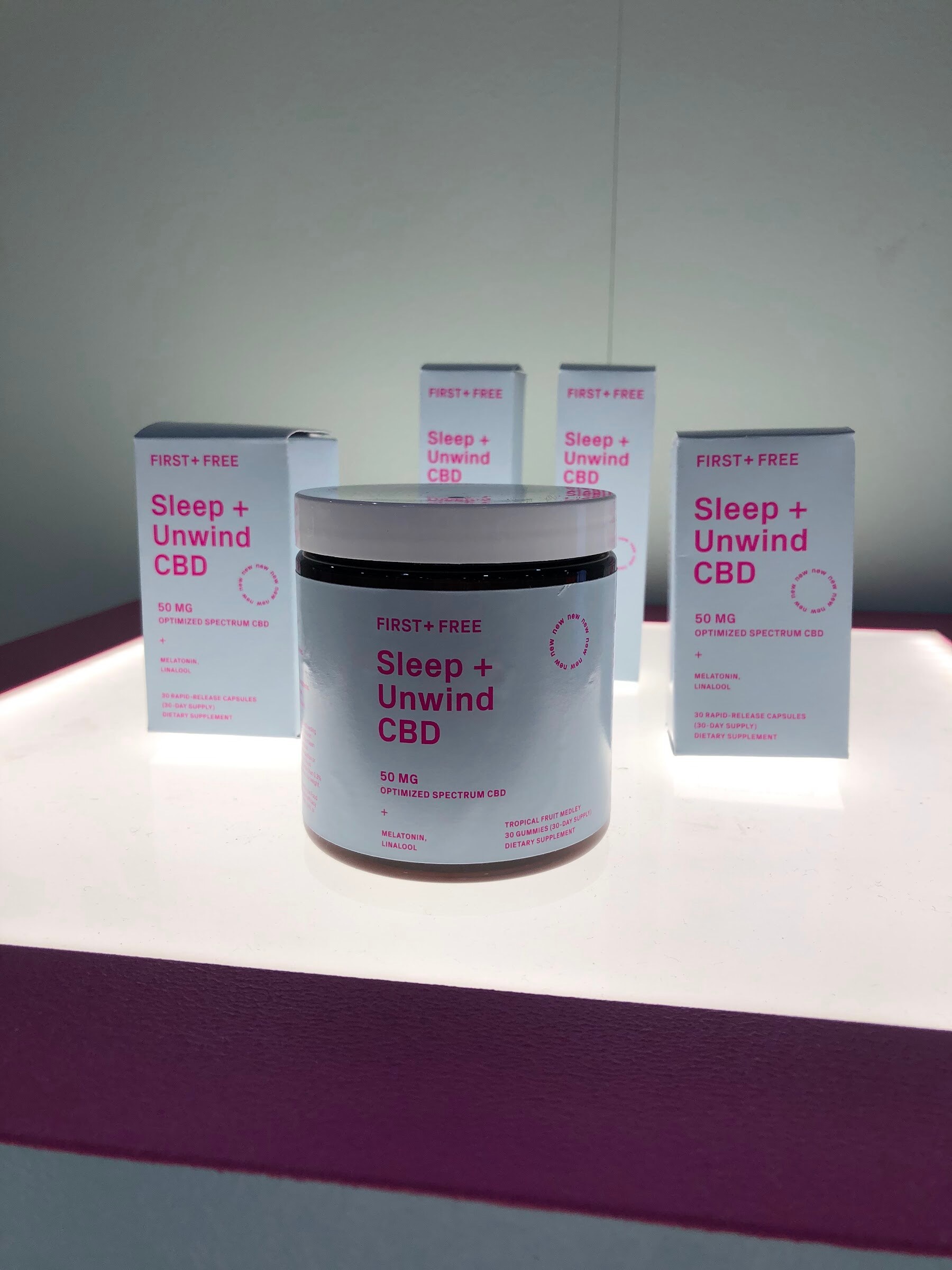 A jar and boxes of First + Free Sleep + Unwind CBD on a lit white display