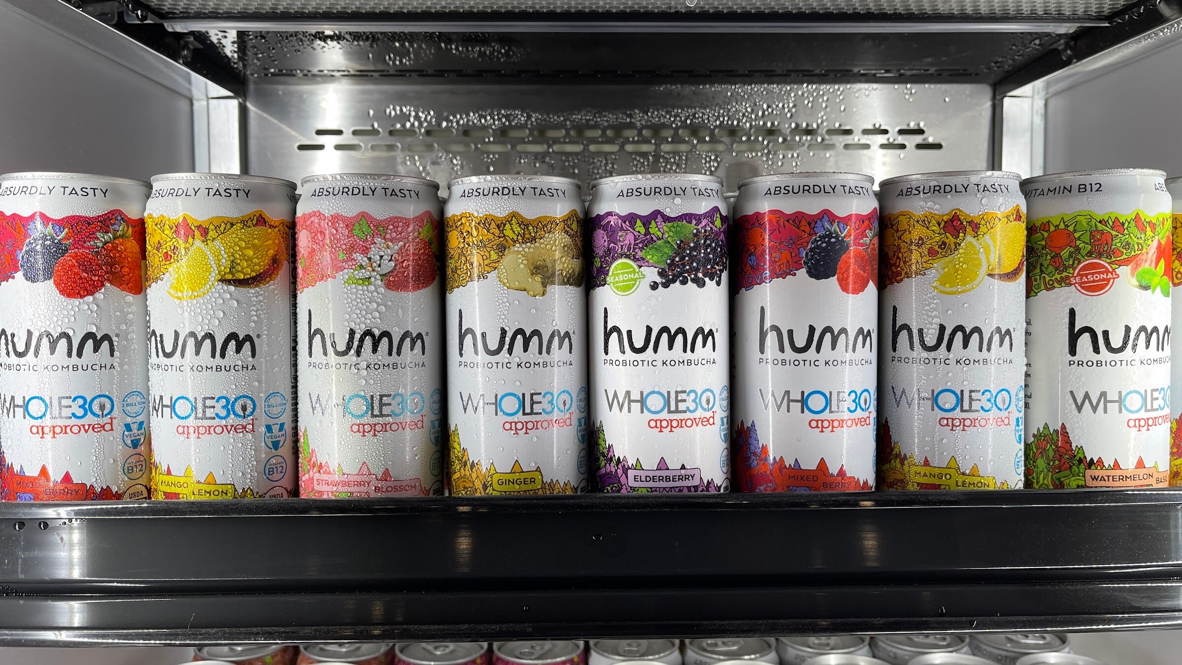 Rows of humm probiotic kombucha cans in several flavors on a refrigerated shelf