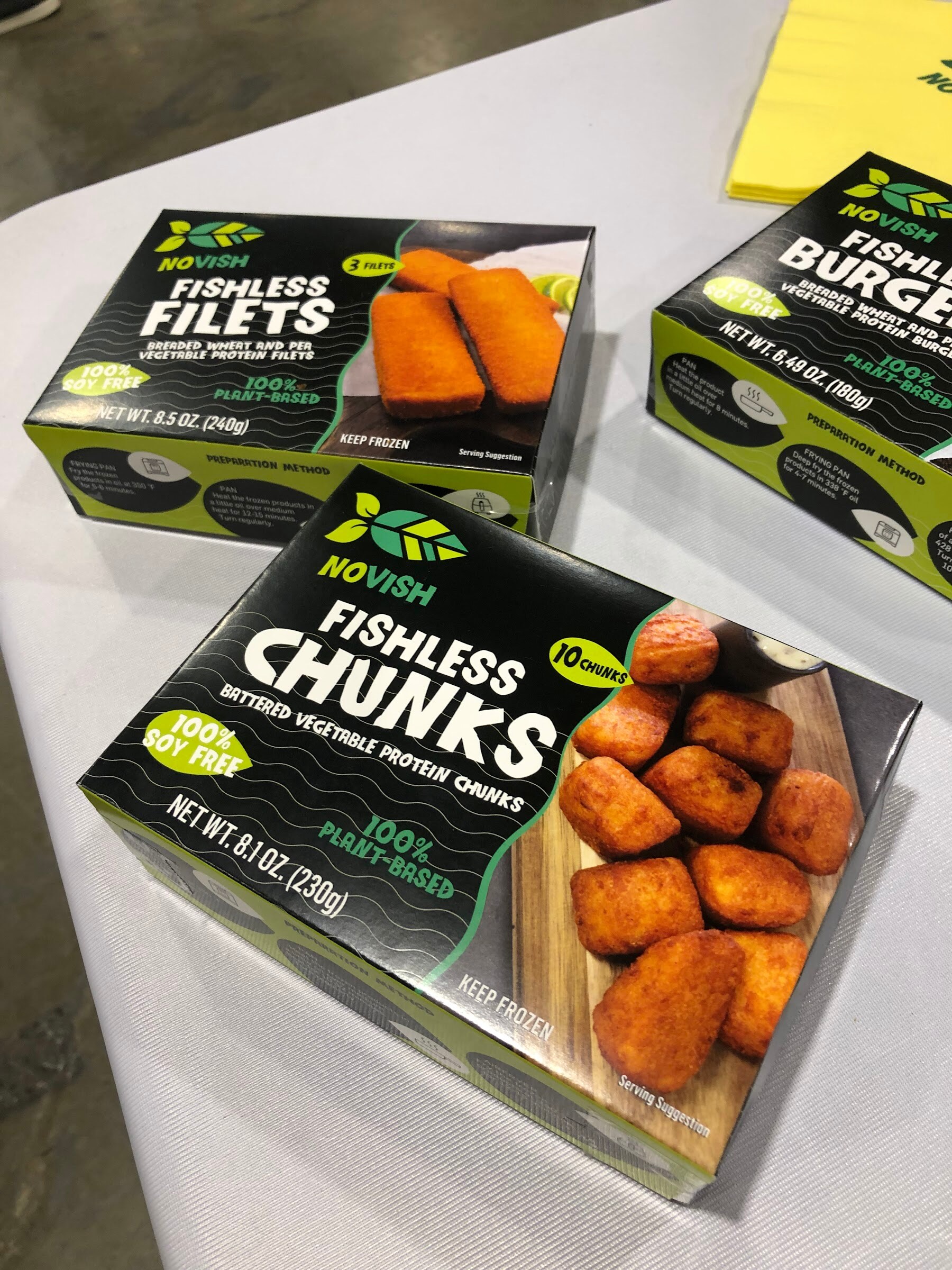 Boxes of NoVish Fishless Chunks, Filets and Burgers on a white table