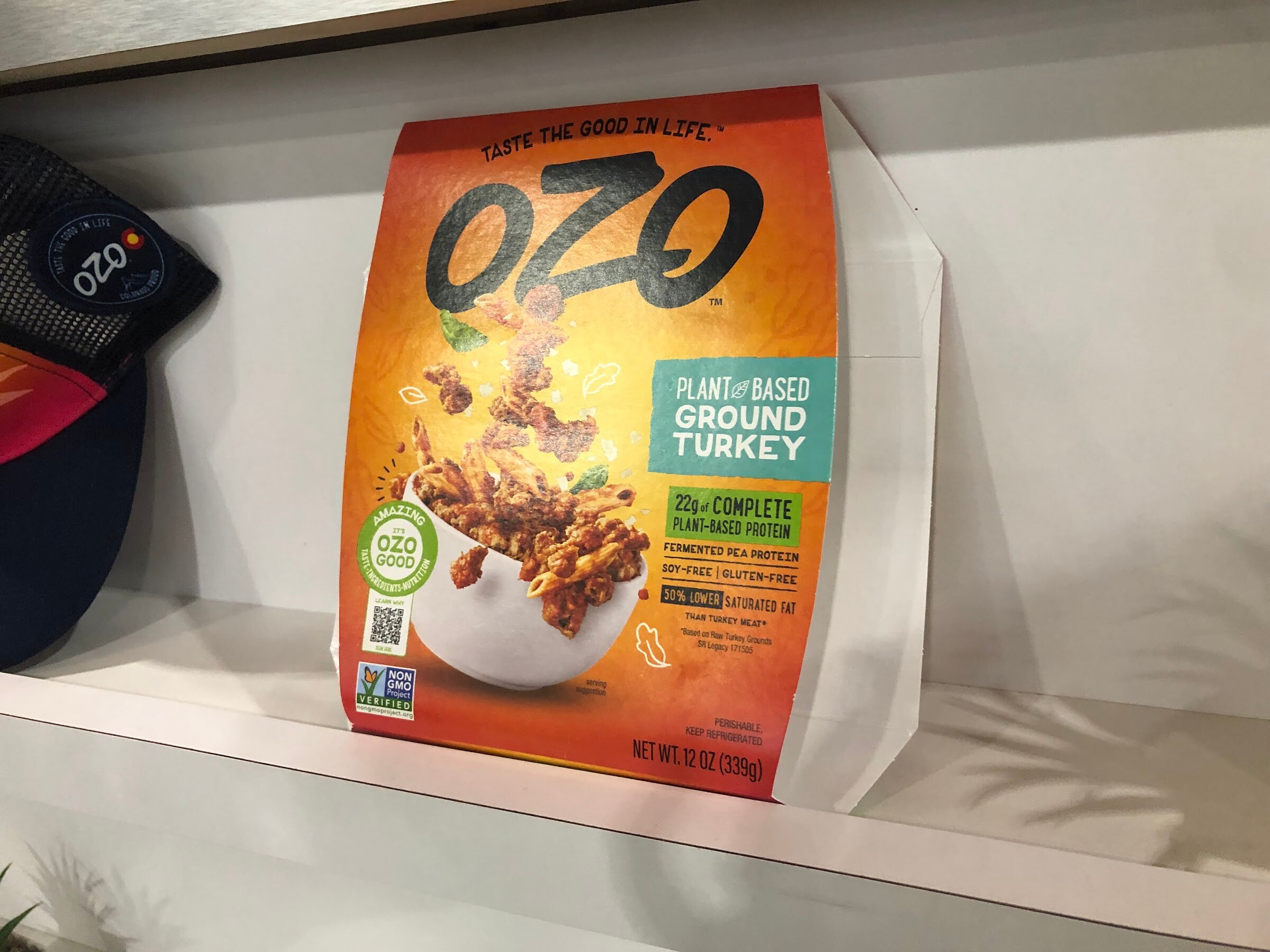 A bag of OZO plant-based ground turkey in orange packaging on a white shelf