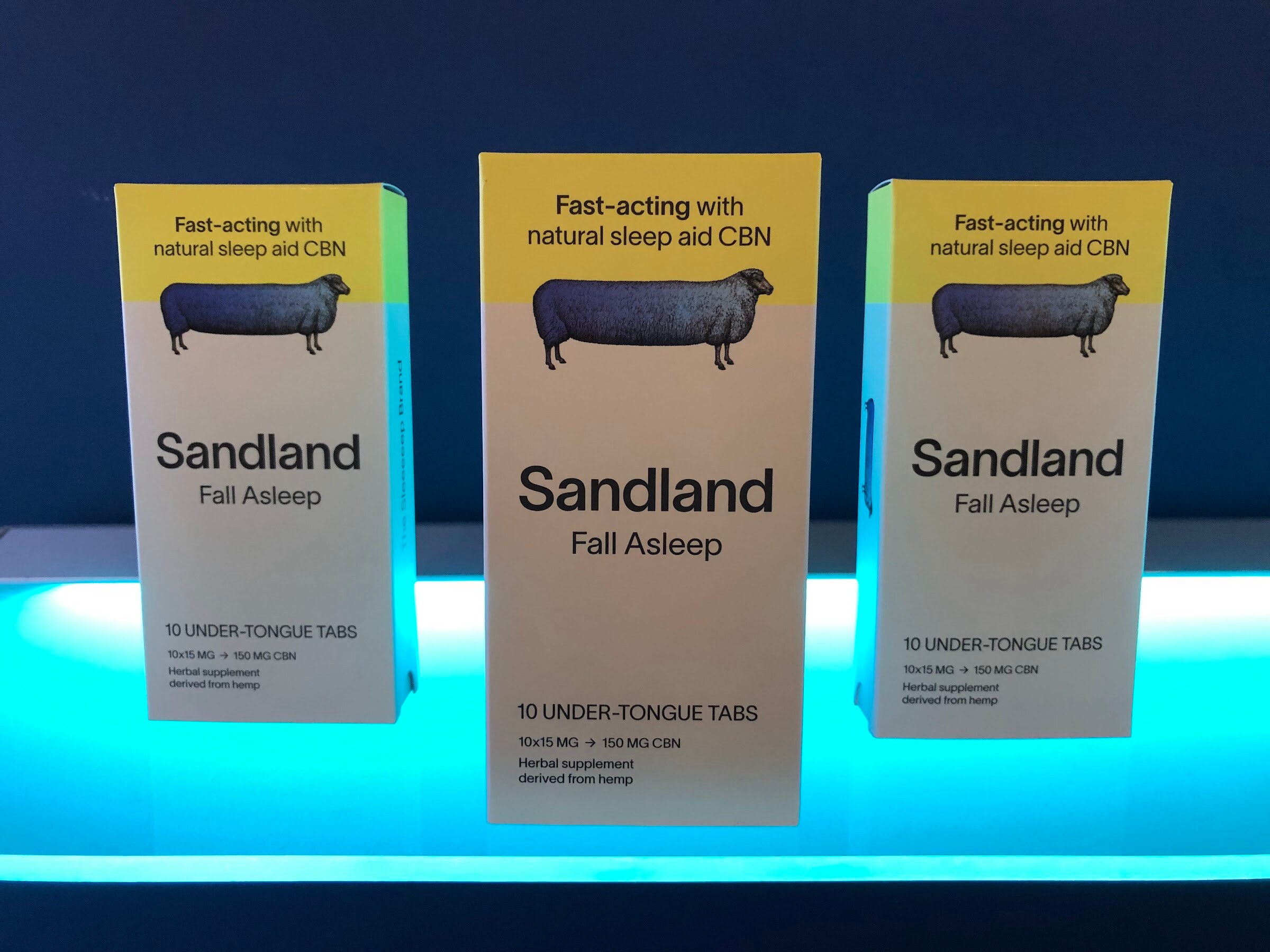 Three Sandland Fall Asleep boxes with a sheep illustration on a glowing blue shelf