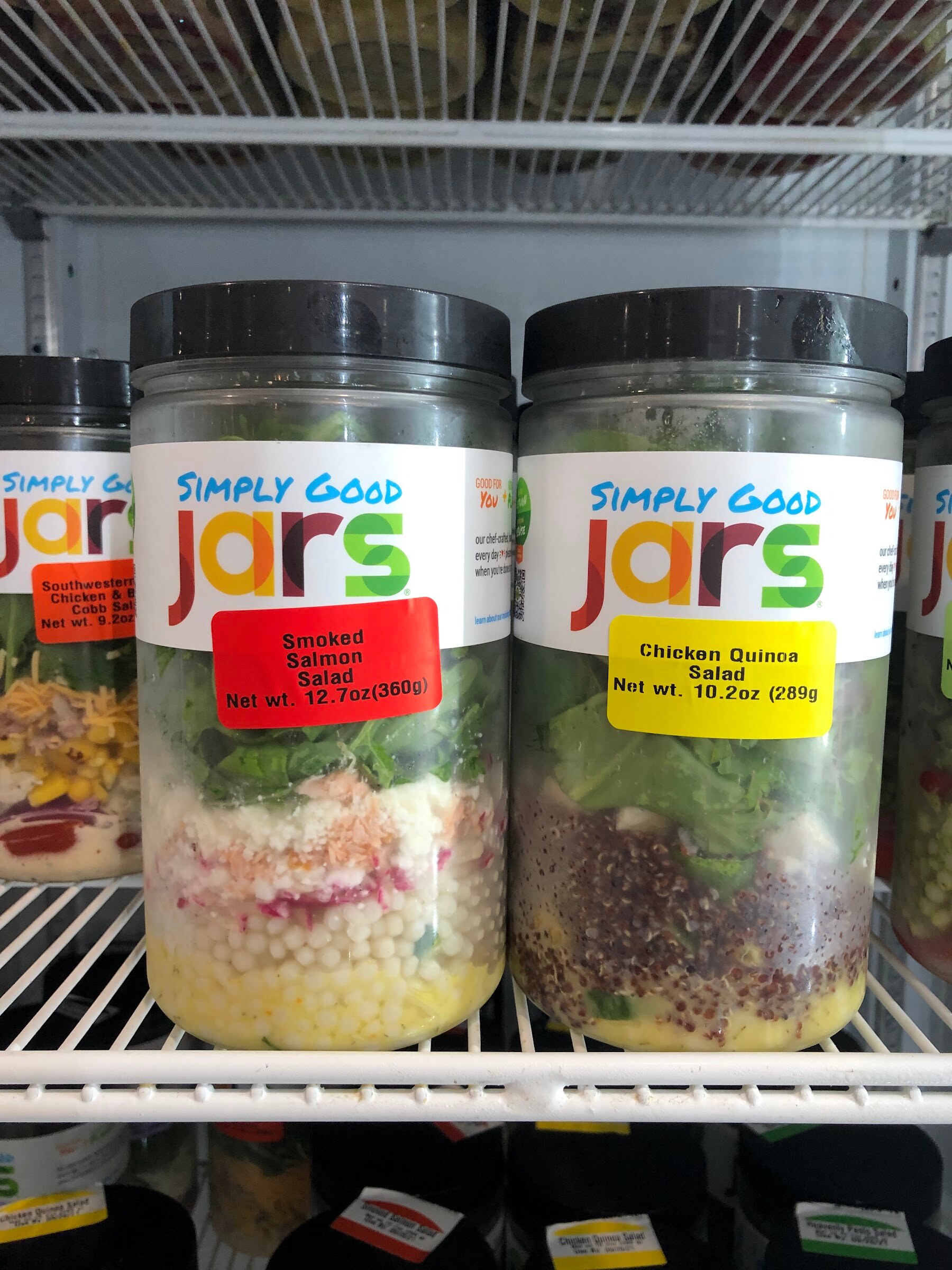 Layered Simply Good Jars salads, smoked salmon and chicken quinoa, on a wire shelf in a cooler