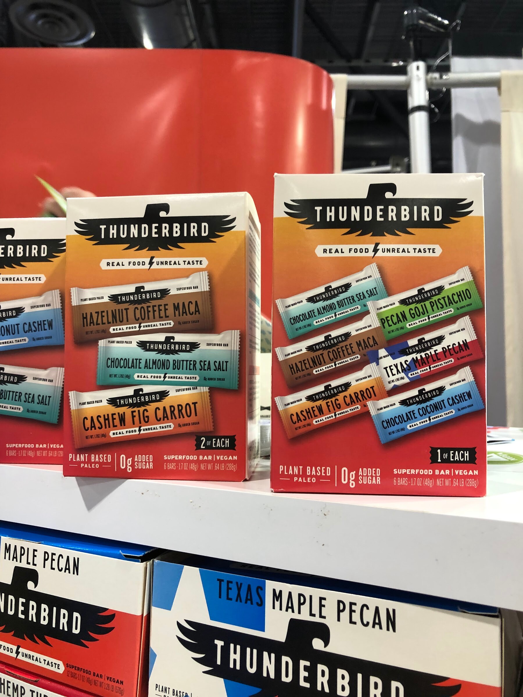 Boxes of Thunderbird real food bars in several flavors stacked above Texas maple pecan boxes