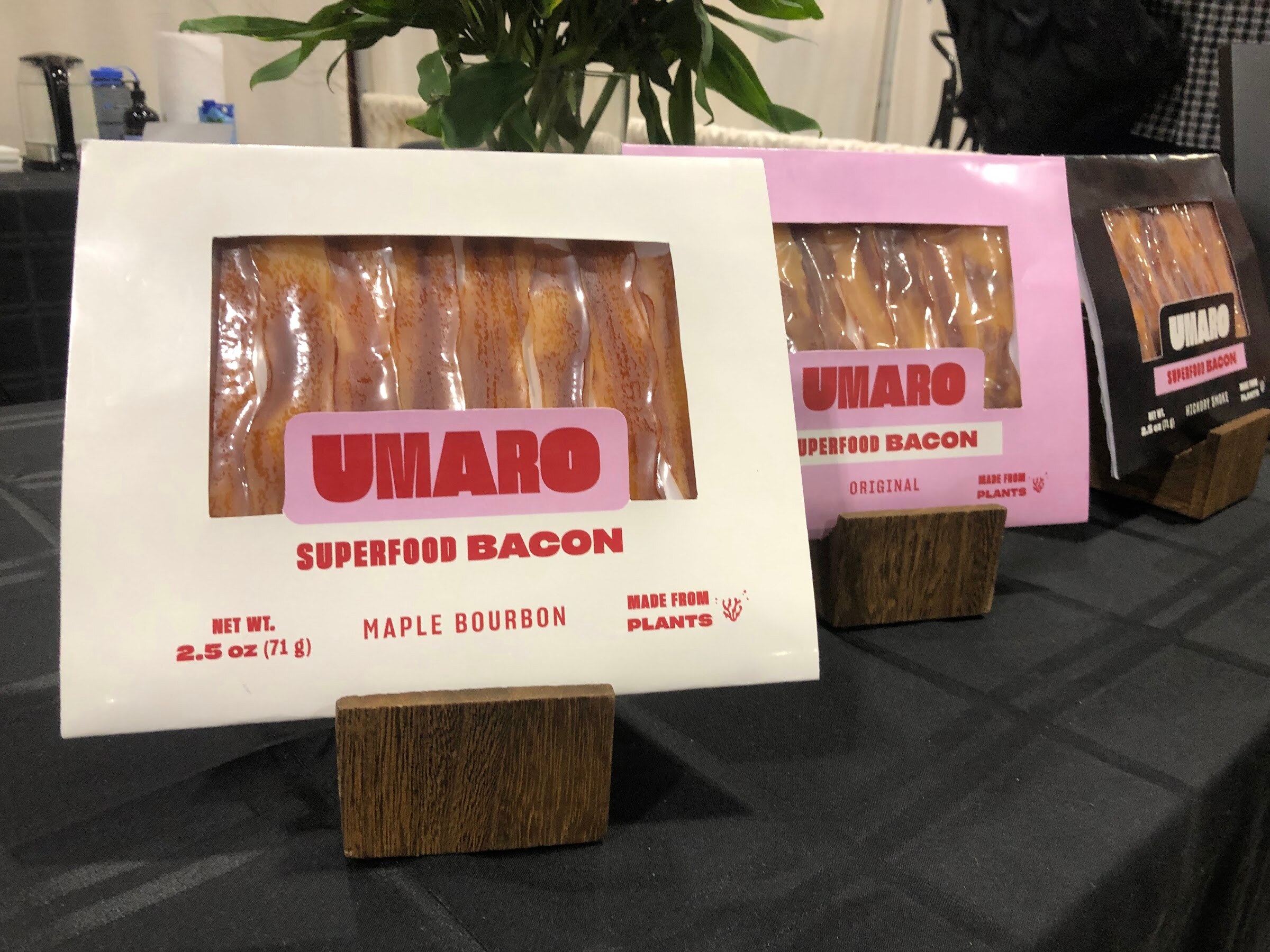 Umaro superfood bacon packages in maple bourbon and original on a black tablecloth
