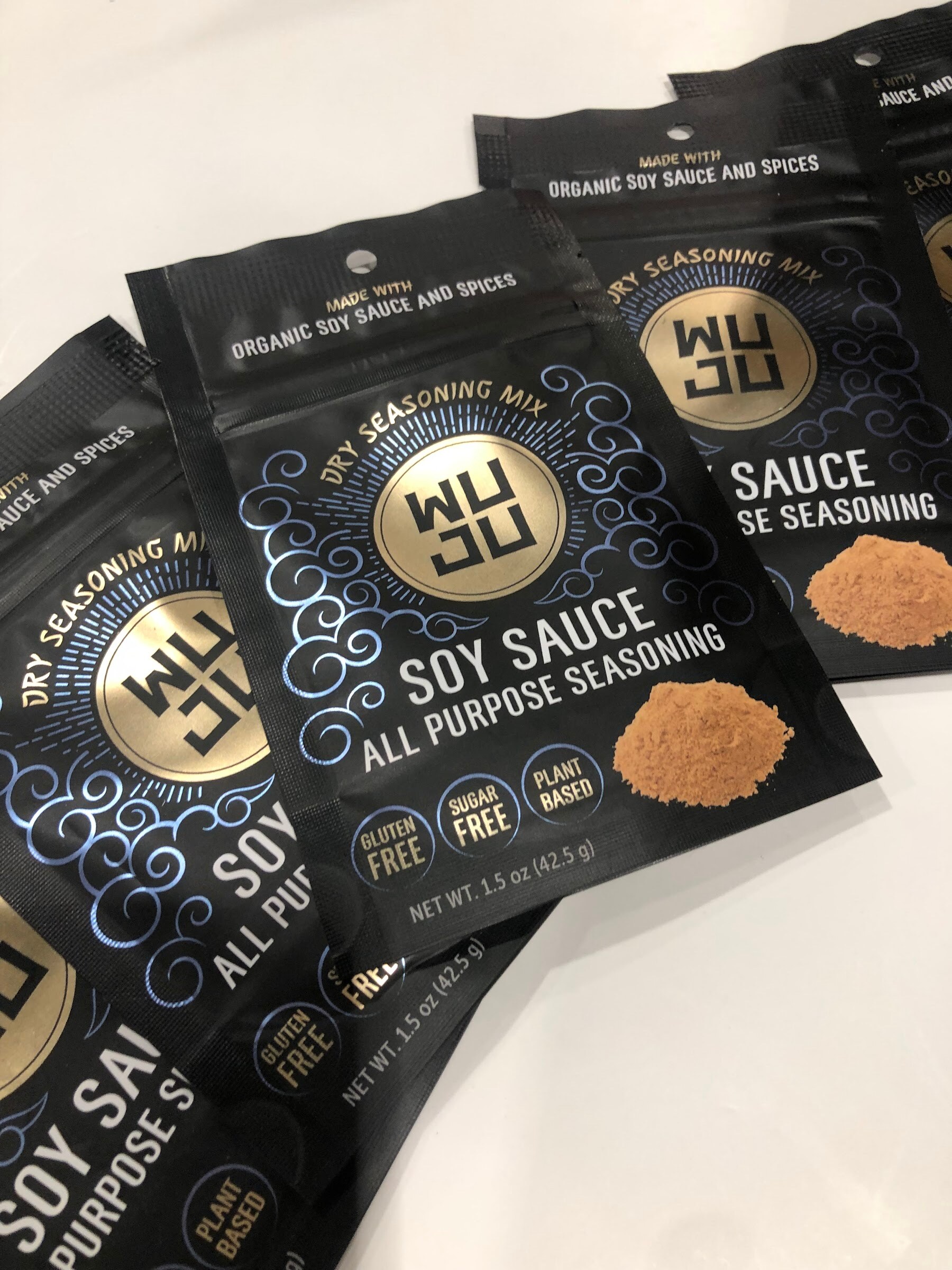 Black WUJU soy sauce all purpose seasoning pouches fanned out on a white table