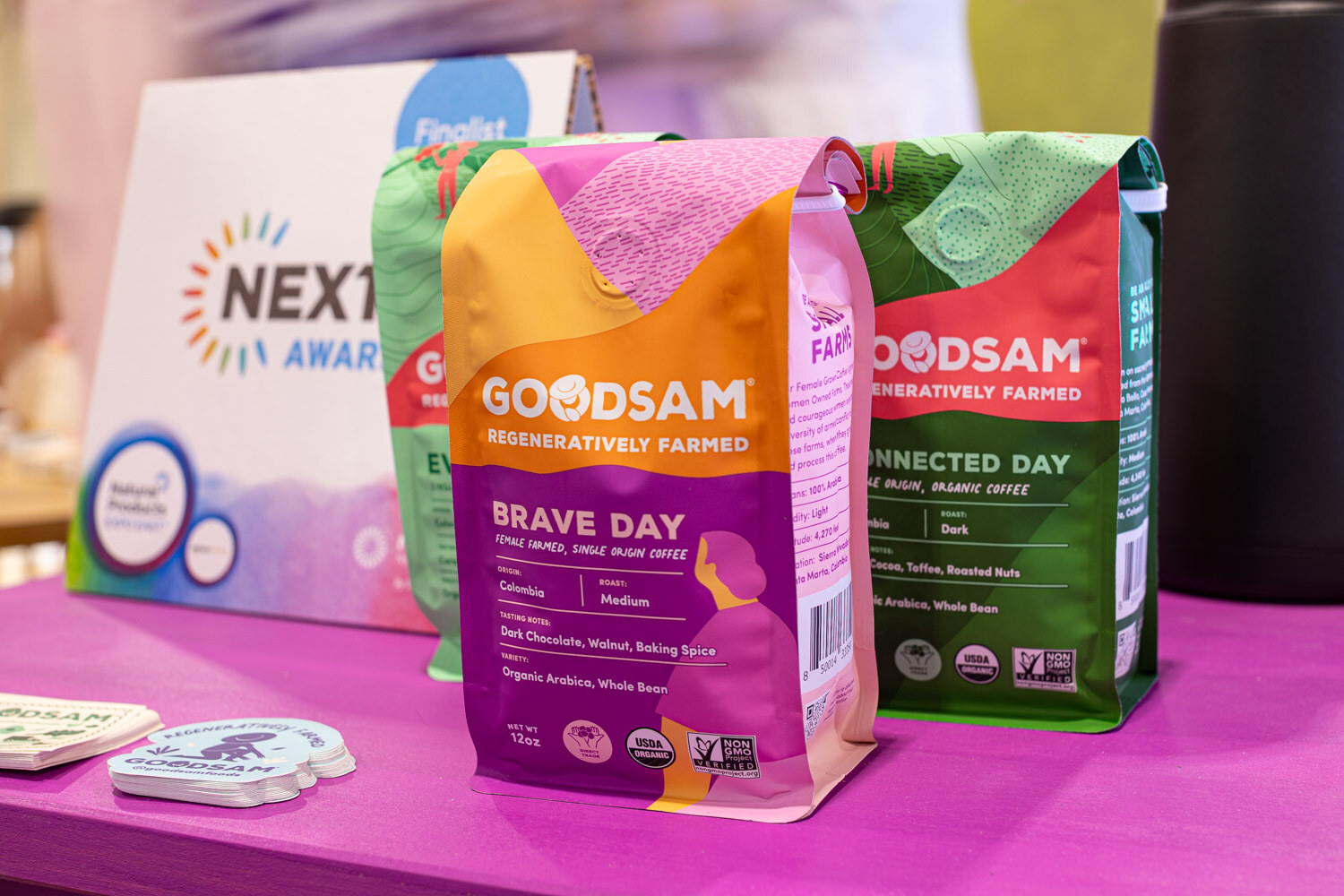 Colorful Goodsam regenerative coffee bags, Brave Day and Connected Day, stand in front of a Nexty Awards sign
