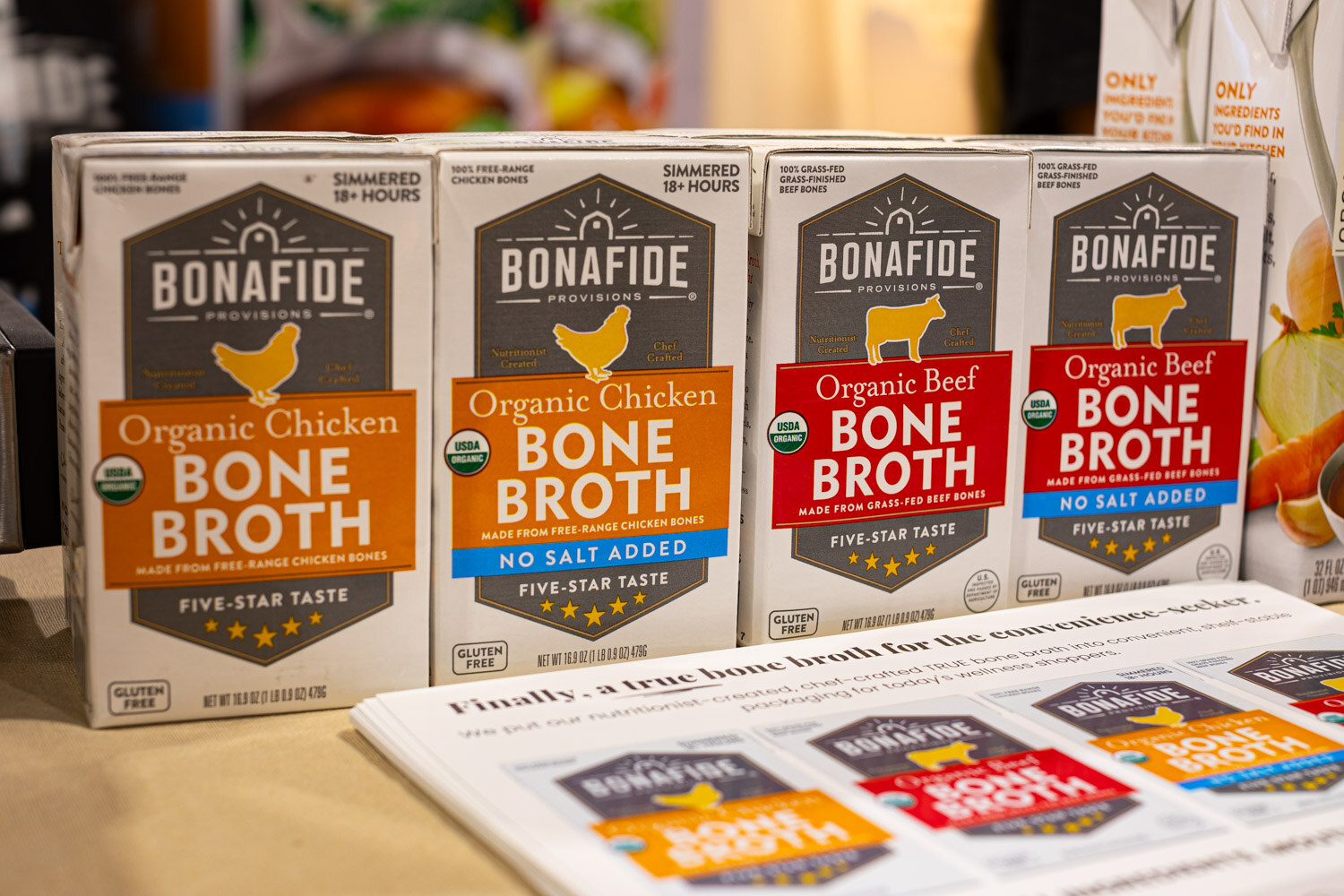 Cartons of Bonafide Provisions organic chicken and beef bone broth stand above a newspaper-style flyer