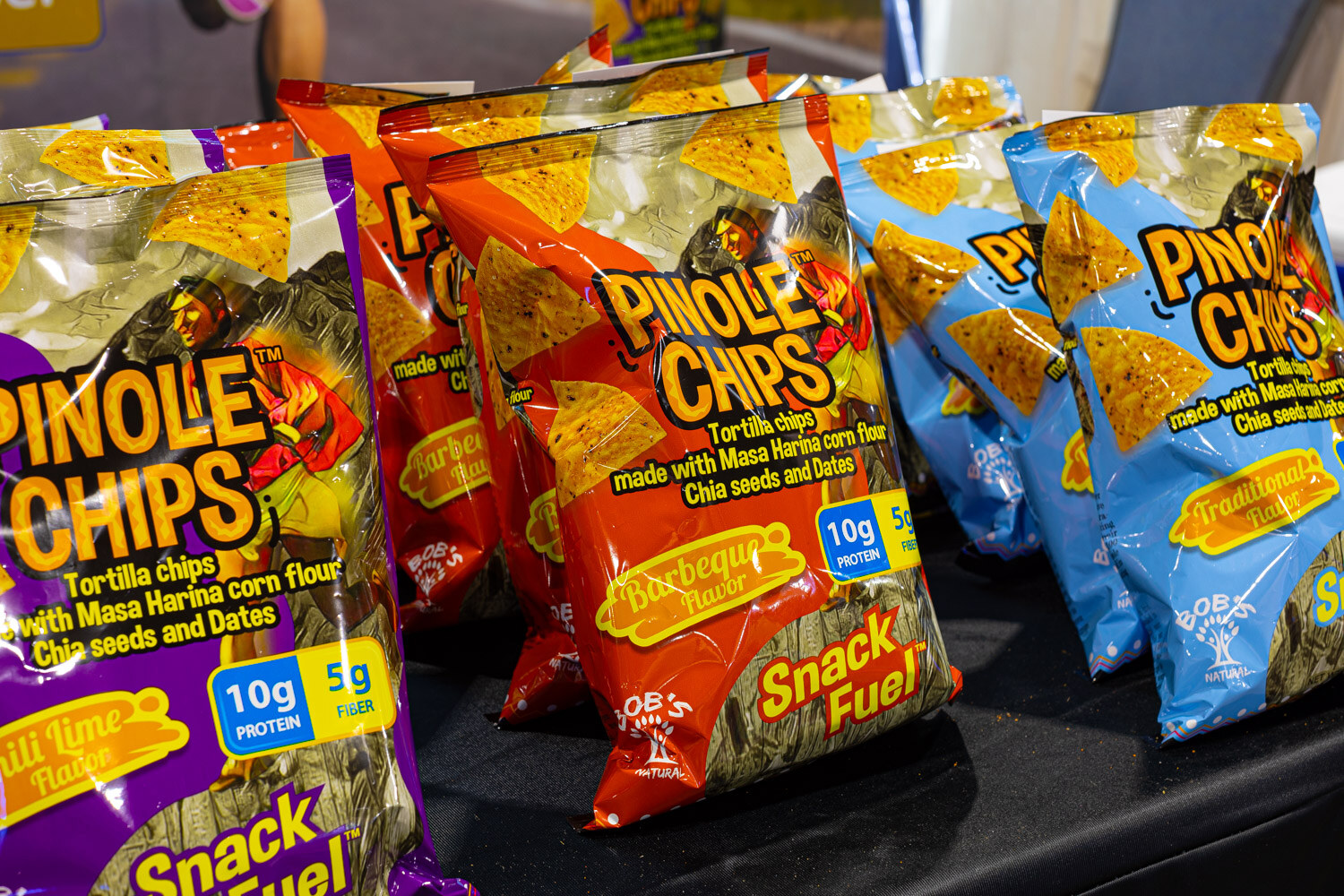 Colorful Pinole Chips tortilla chip bags in barbecue and other flavors are piled on a table