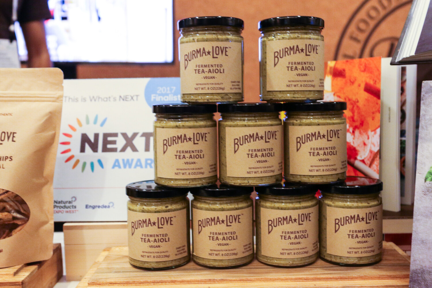 Pyramid of Burma Love Fermented Tea-Aioli jars beside a Natural Products Expo West NEXTY Awards 2017 Finalist card.