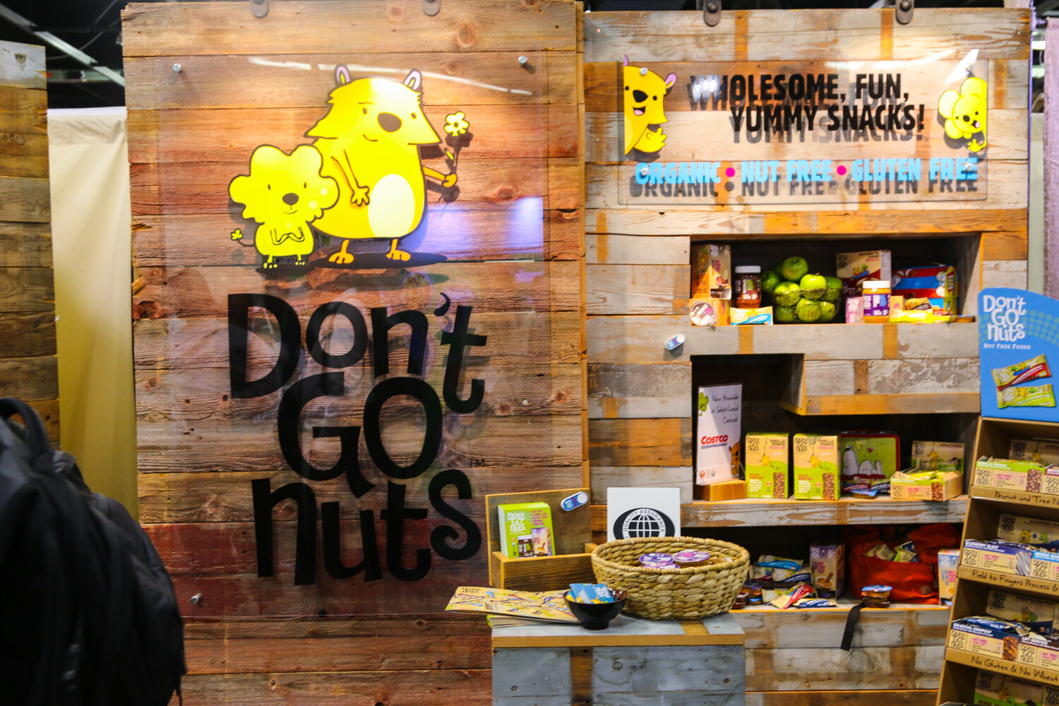Wooden booth wall with a yellow animal logo and the words Don't Go Nuts, shelves of boxed snacks and a woven basket.