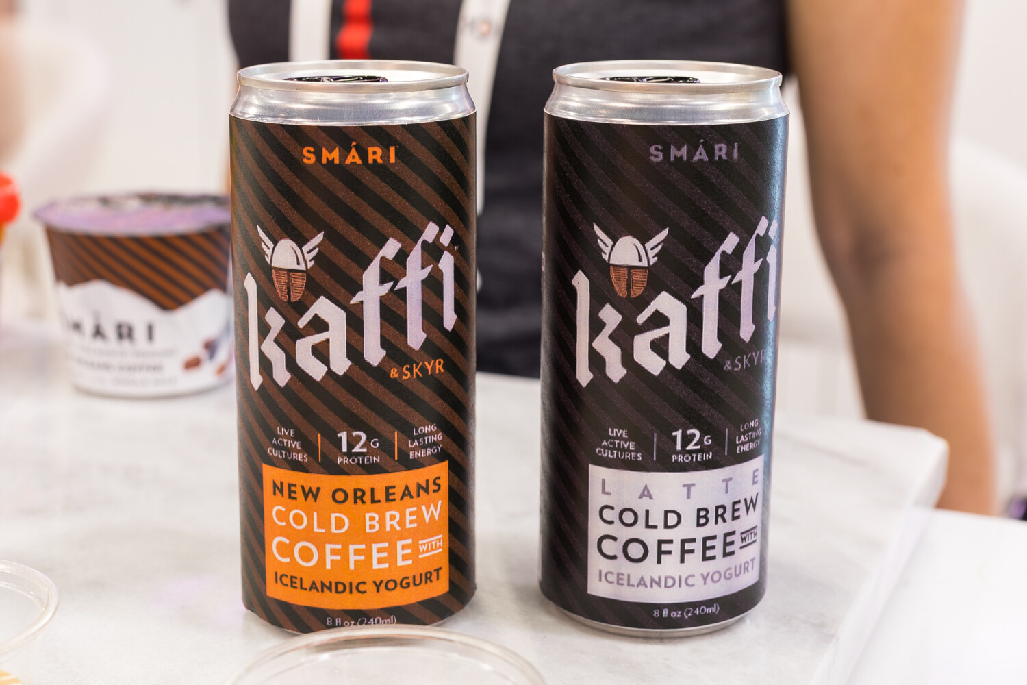 Two Kaffi cans, one New Orleans cold brew and one latte, with a Smari yogurt cup behind them.