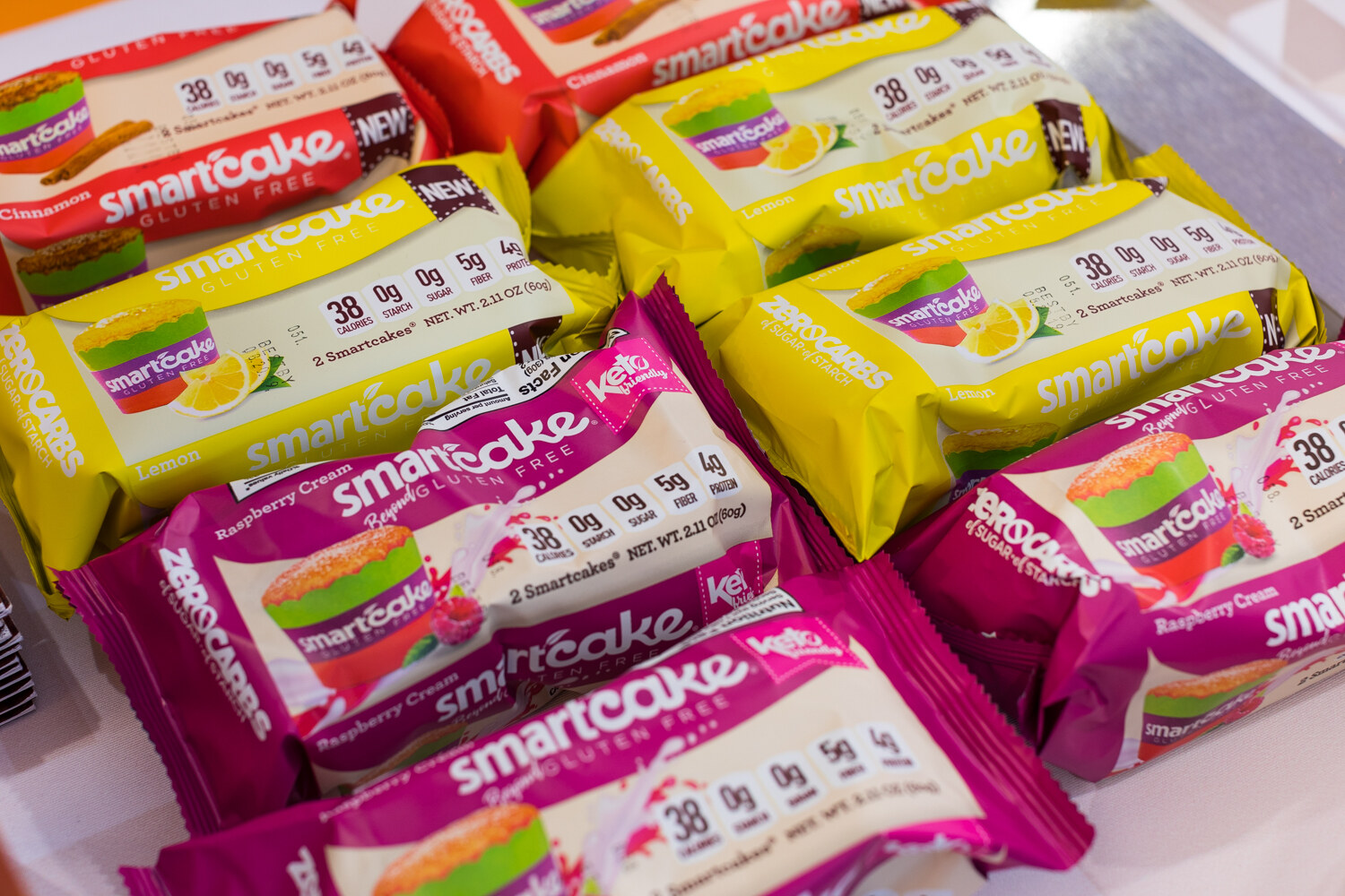Many yellow, red and pink Smartcake packages overlapping each other in a tray.