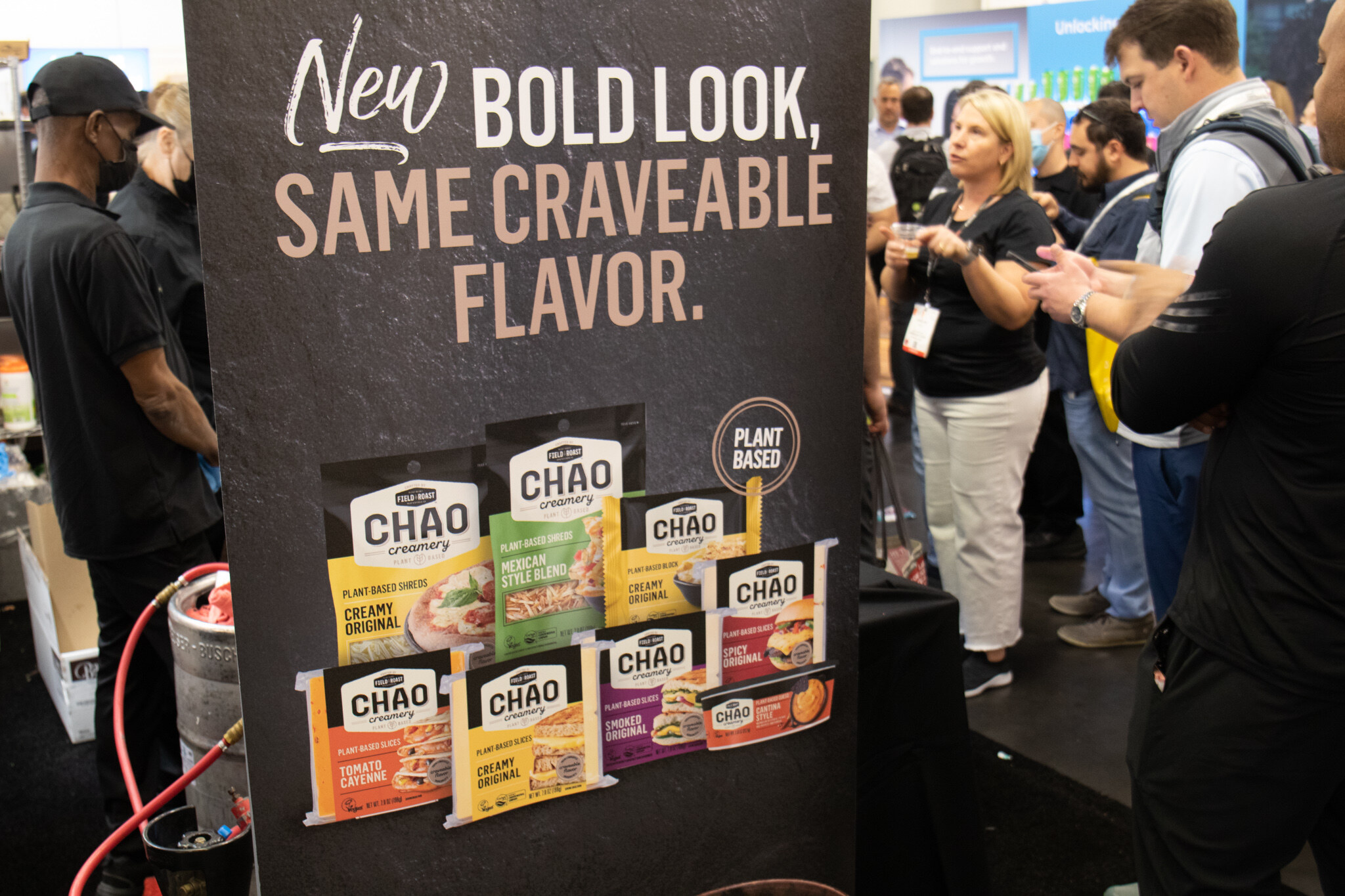 A Chao Creamery plant-based slices sign reading New bold look, same craveable flavor stands in front of attendees at the booth