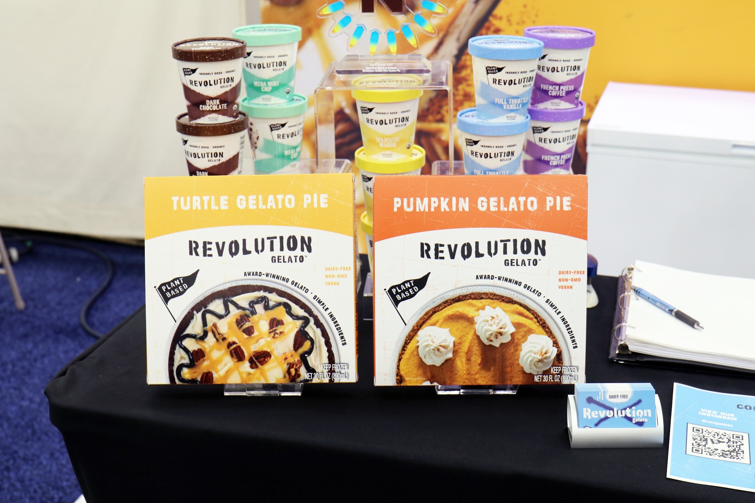 Revolution Gelato turtle and pumpkin gelato pies stand in front of tubs of Revolution gelato on a black table