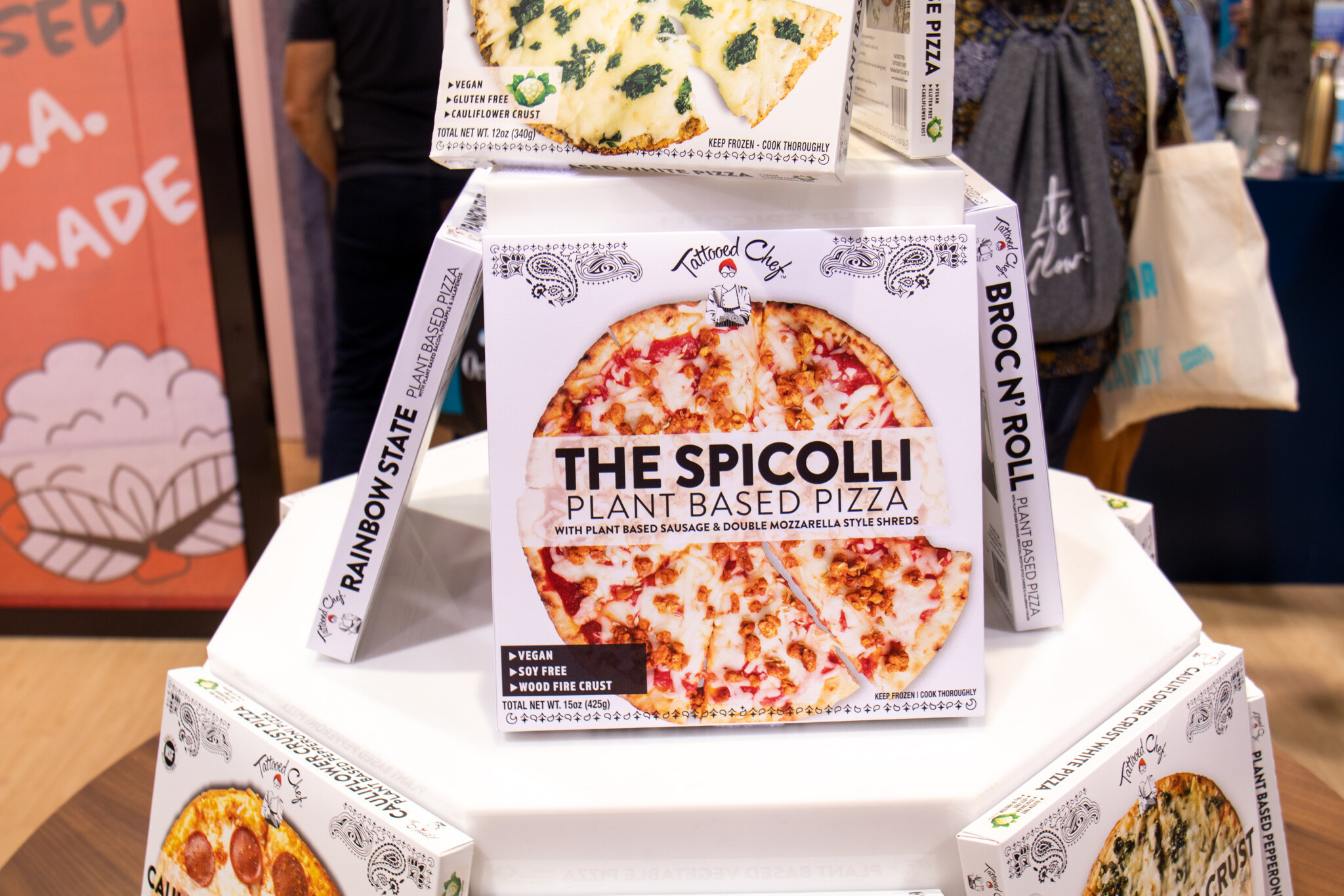 A box of The Spicolli plant based pizza stands in a tiered white display with other frozen pizza boxes