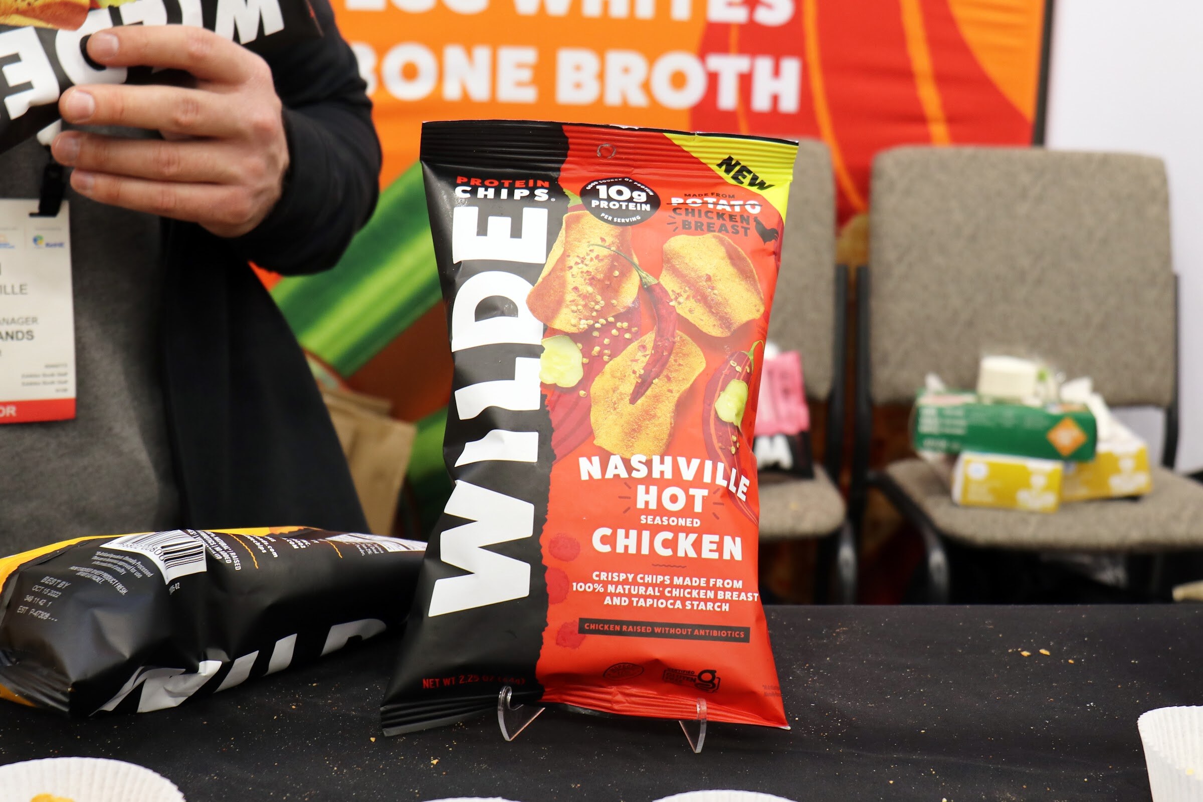 A bag of Wilde Nashville Hot protein chips stands on a black table at the booth
