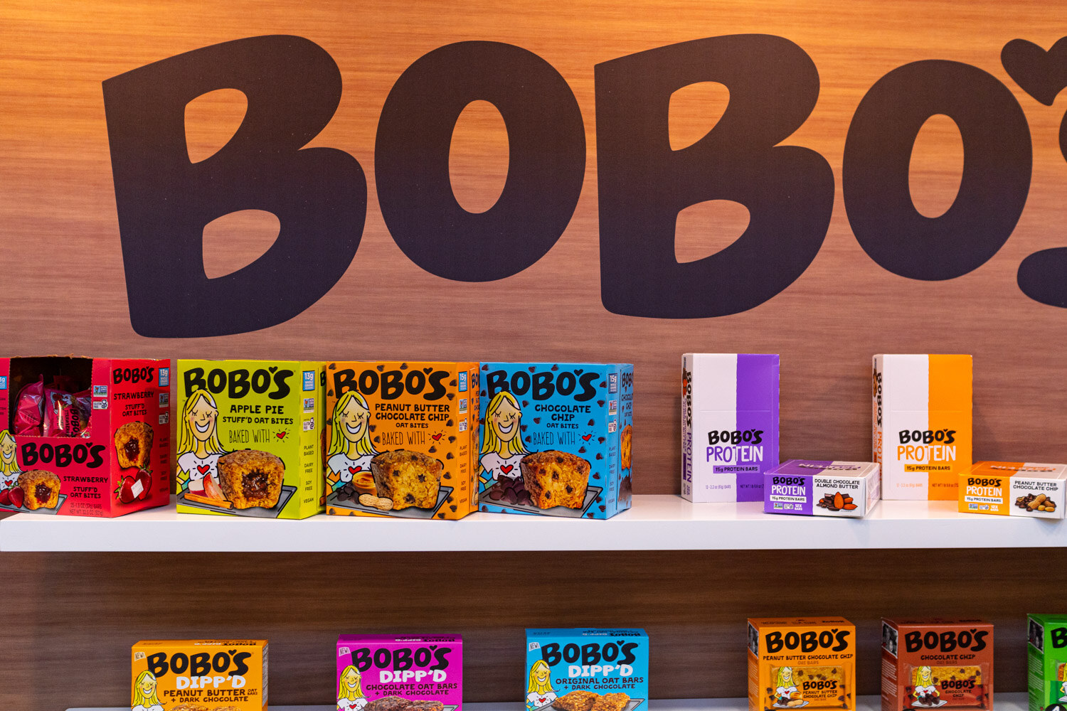 A Bobo's sign above shelves of oat bars and a counter display of peanut butter and chocolate oat bars