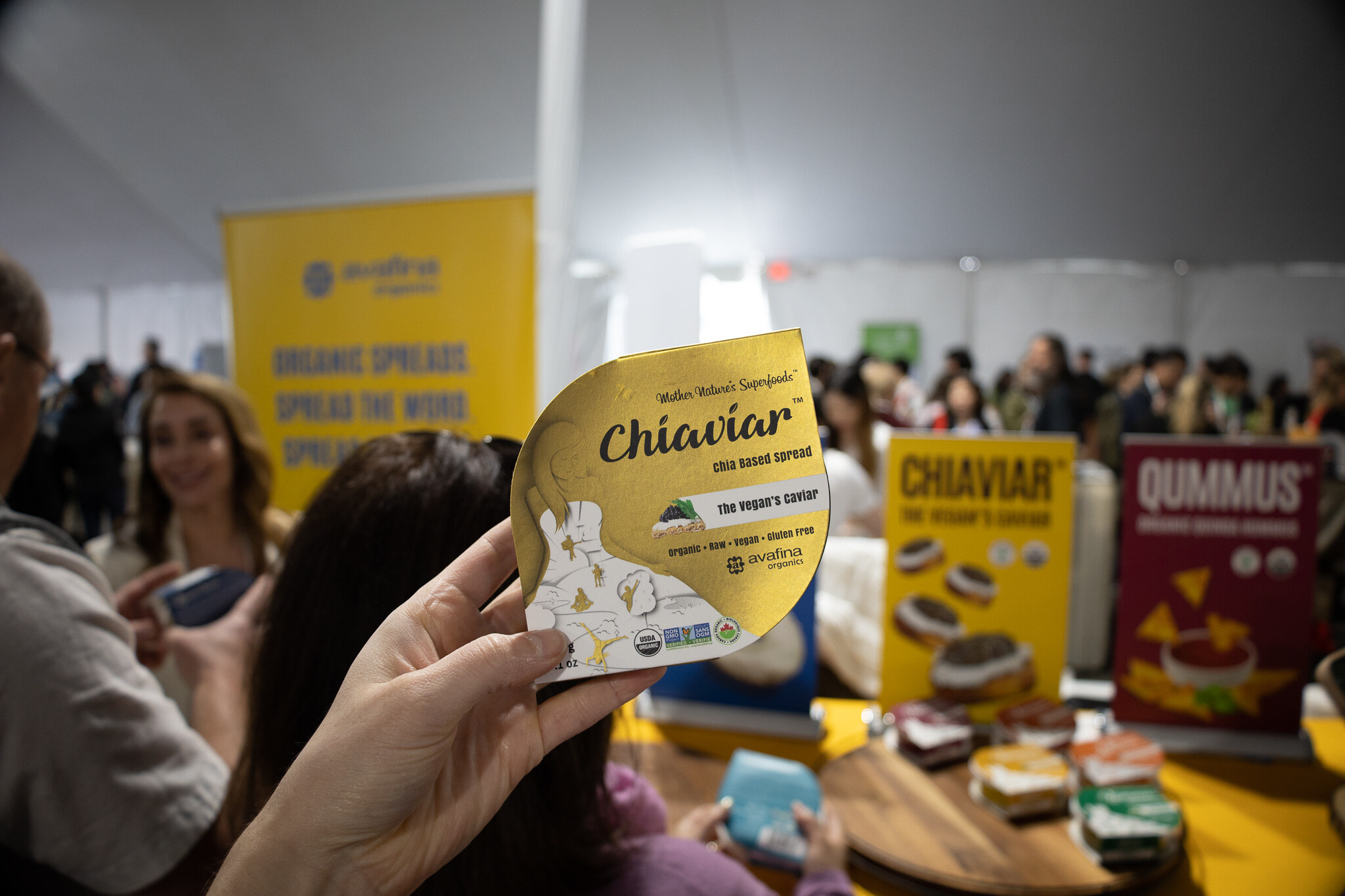 A hand holds a Chiaviar package at a crowded booth in the tent