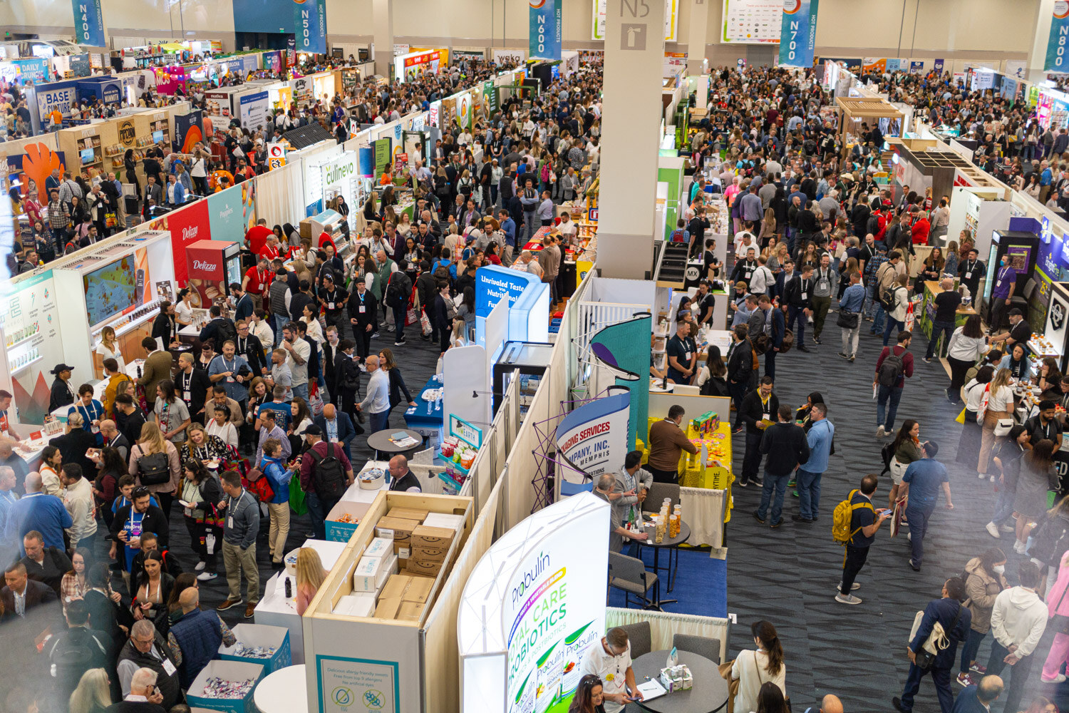 A high view looking down on crowded exhibit hall aisles and booths