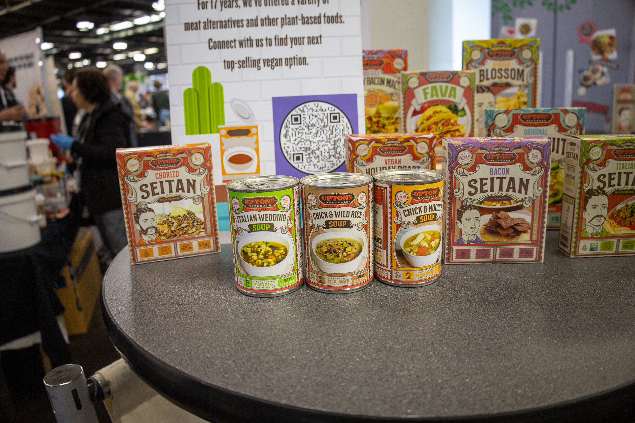 A round table of canned and boxed seitan products at a booth
