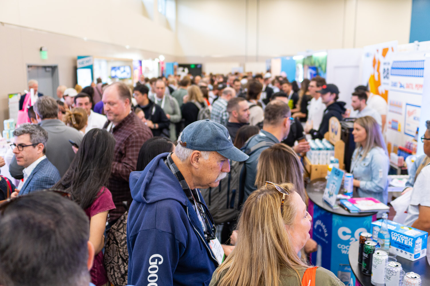 A tightly packed group of attendees at a booth-lined aisle in the exhibit hall