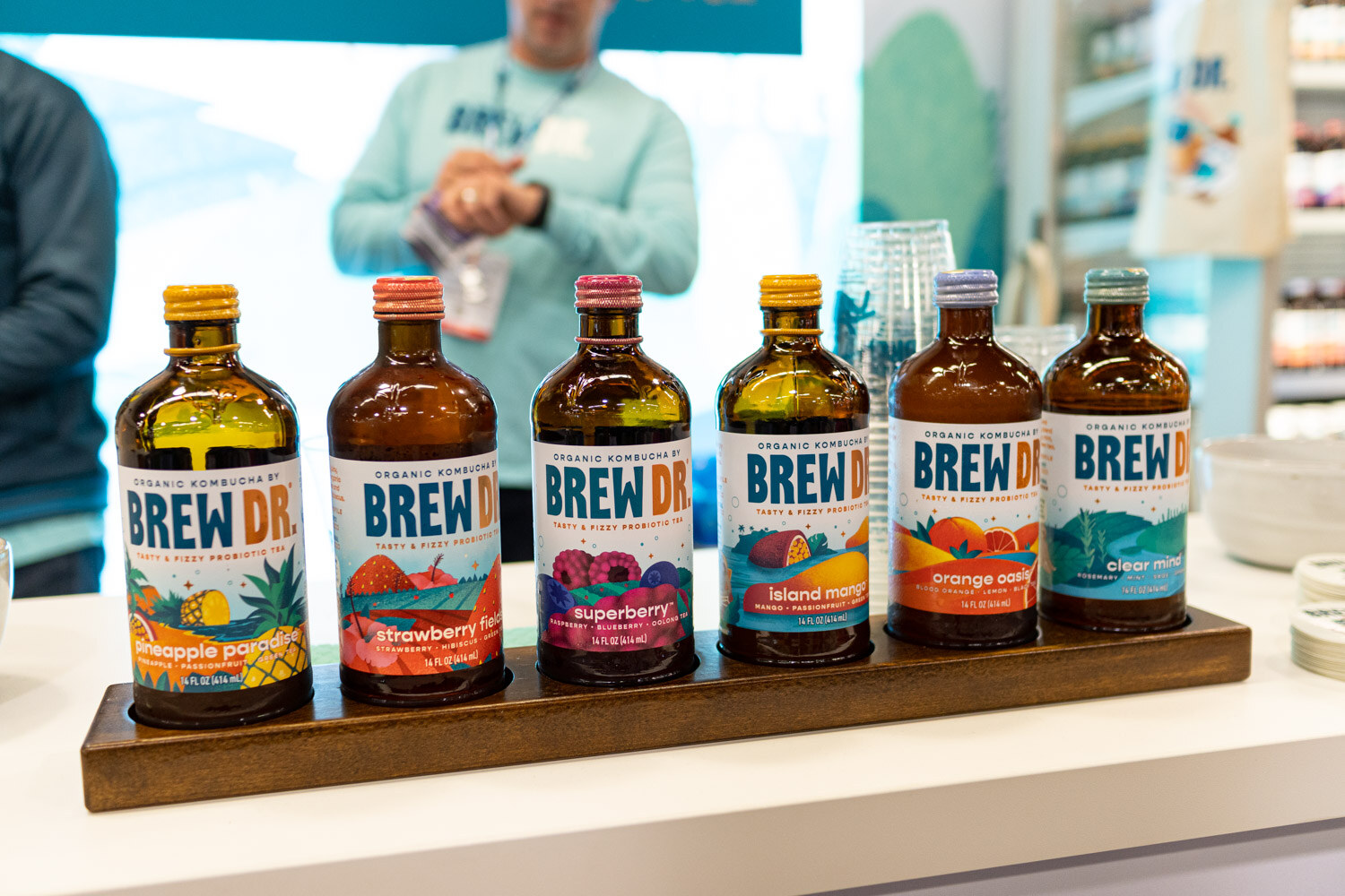 A row of Brew Dr. Kombucha bottles in several flavors on a wooden stand
