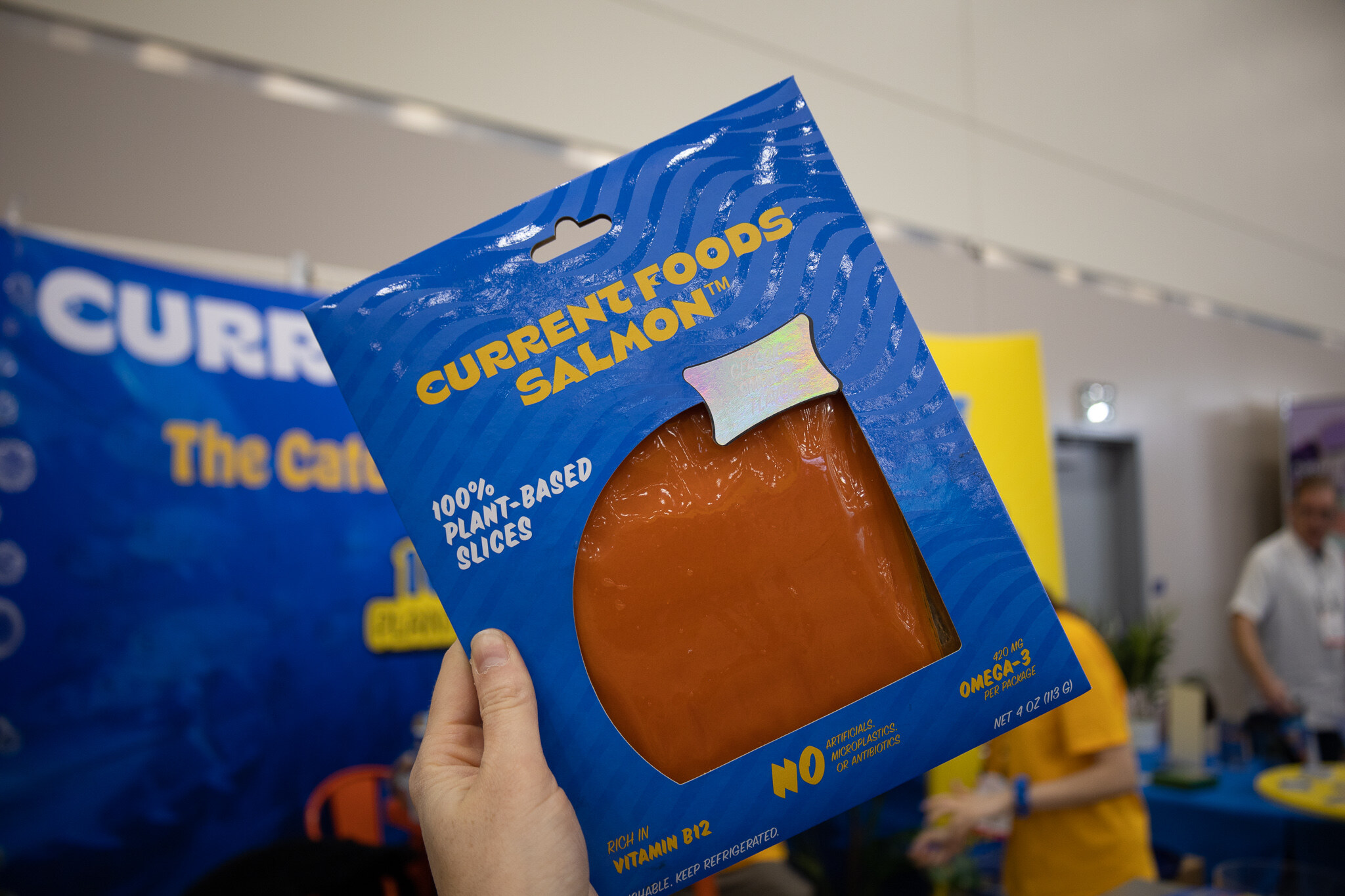 A hand holds a package of Current Foods plant-based salmon