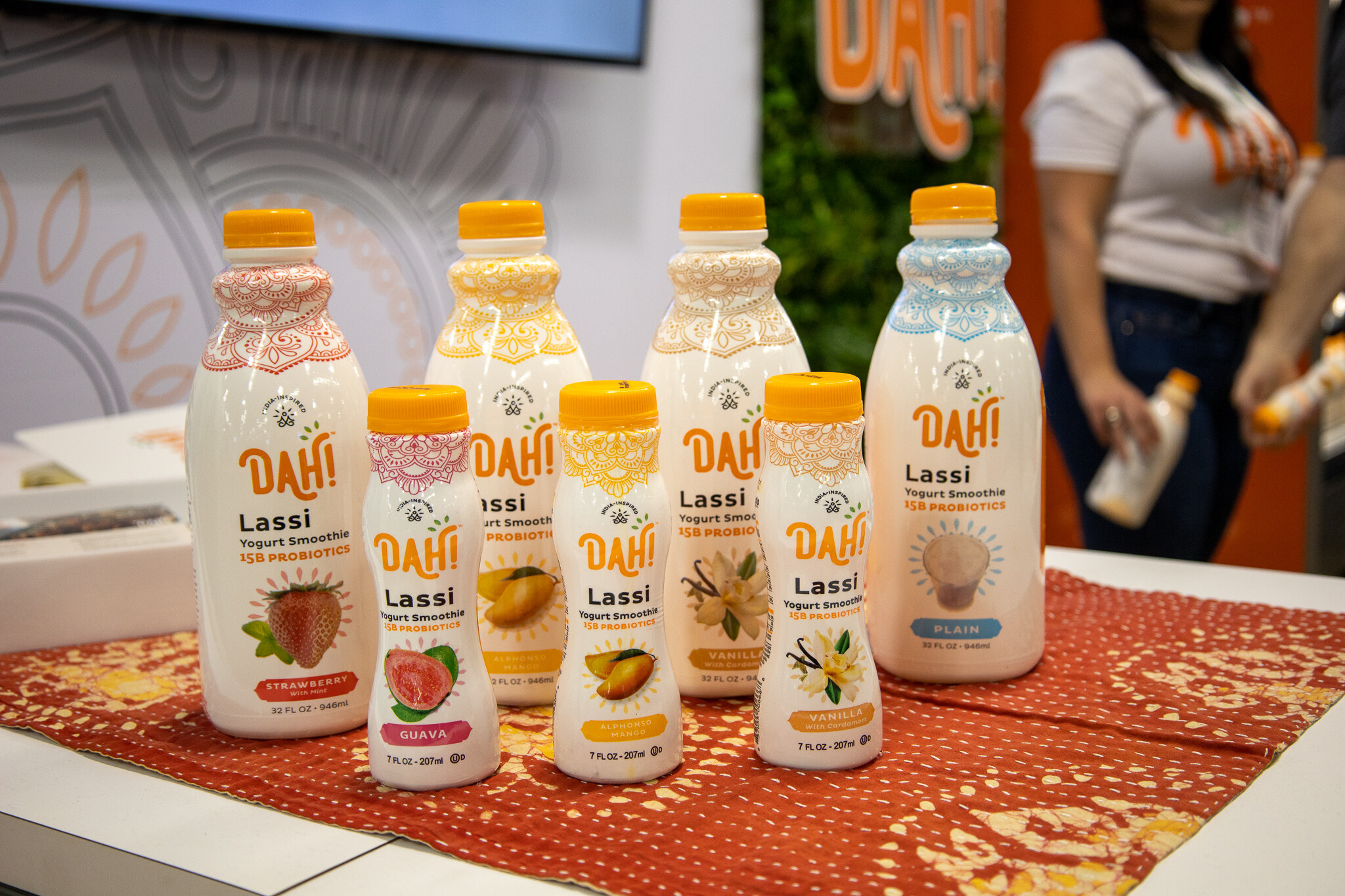Dahi lassi bottles in several flavors arranged on a red patterned cloth