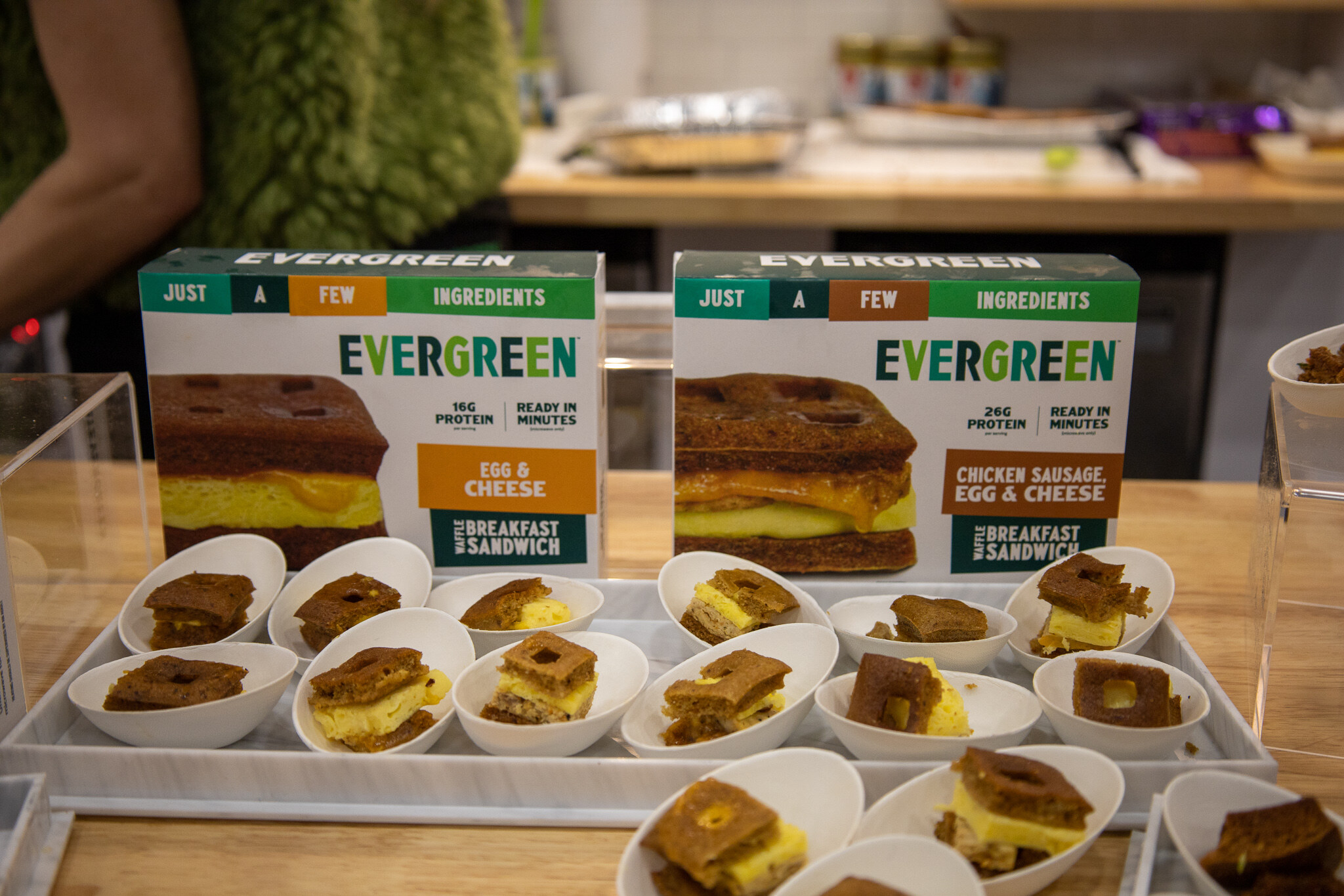 Evergreen breakfast sandwich boxes behind trays of sliced samples