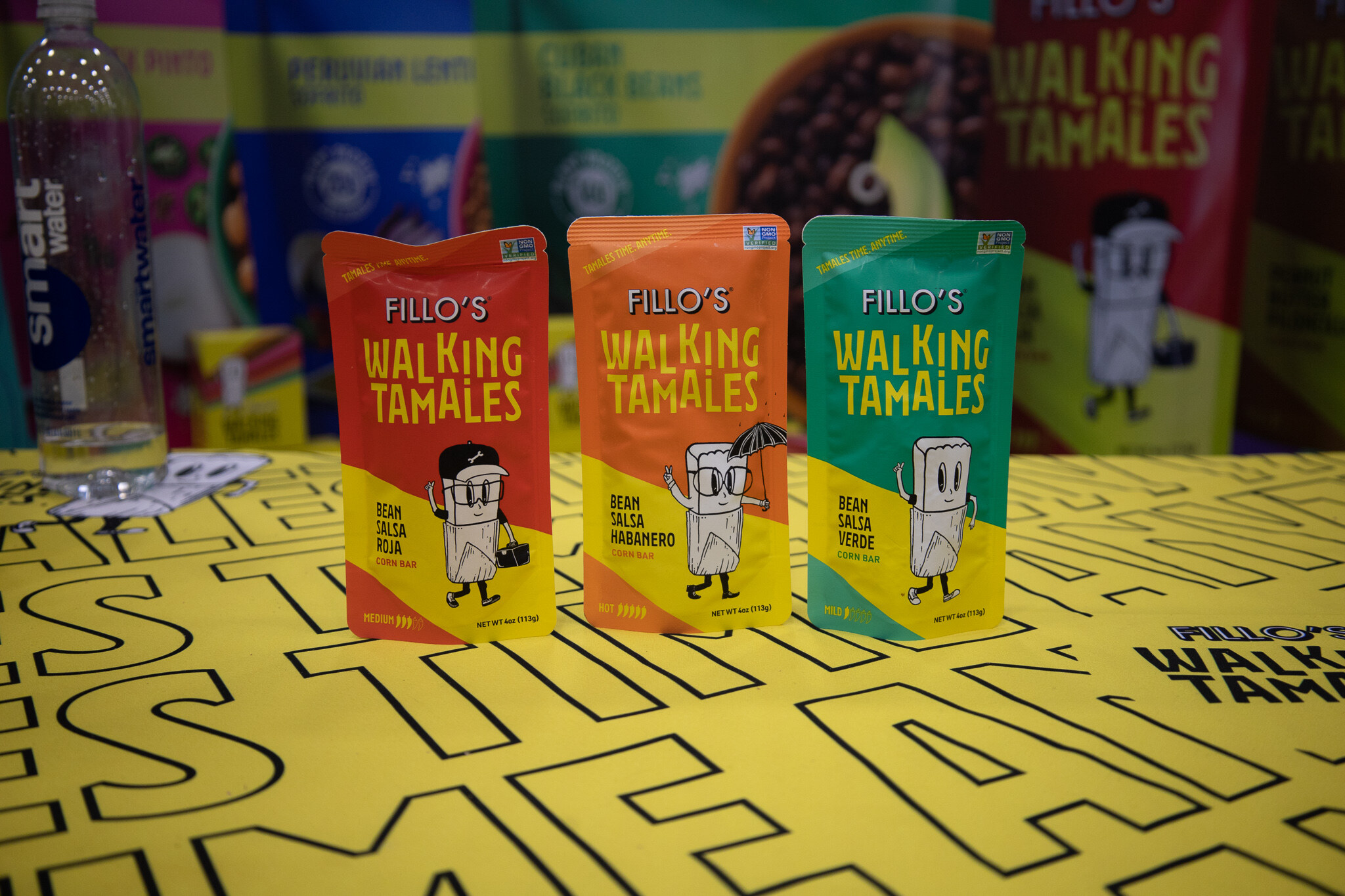 Three Fillo's Walking Tamales packages on a yellow lettered tablecloth