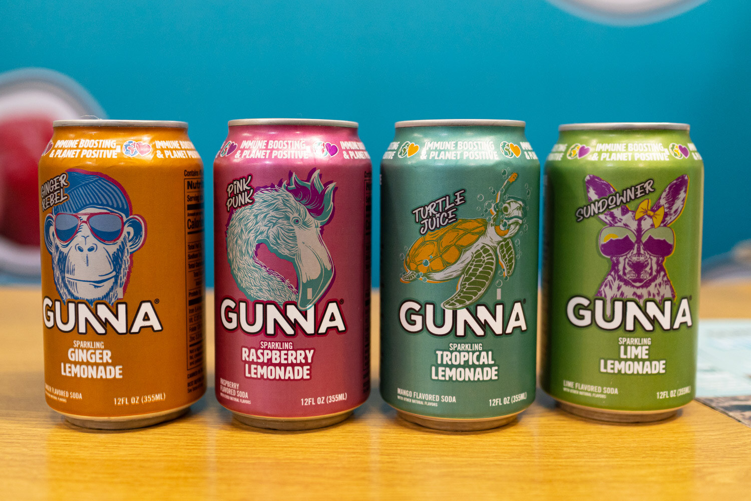 Four Gunna lemonade cans with animal illustrations in ginger, raspberry, tropical and lime flavors