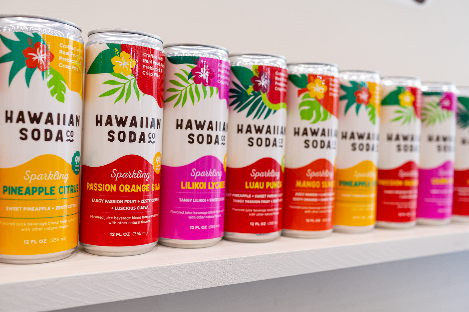 A row of Hawaiian Soda cans in bright flavors including pineapple citrus and passion orange