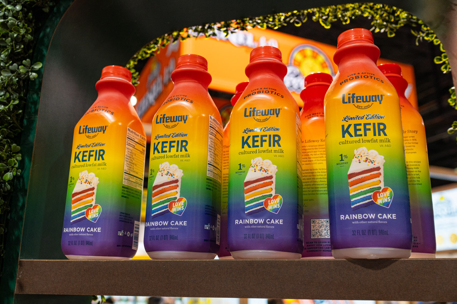 Lifeway kefir bottles in rainbow cake and other flavors on a dark shelf