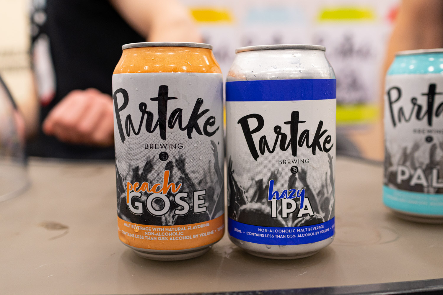 Three Partake Brewing cans including a peach gose and a hazy IPA