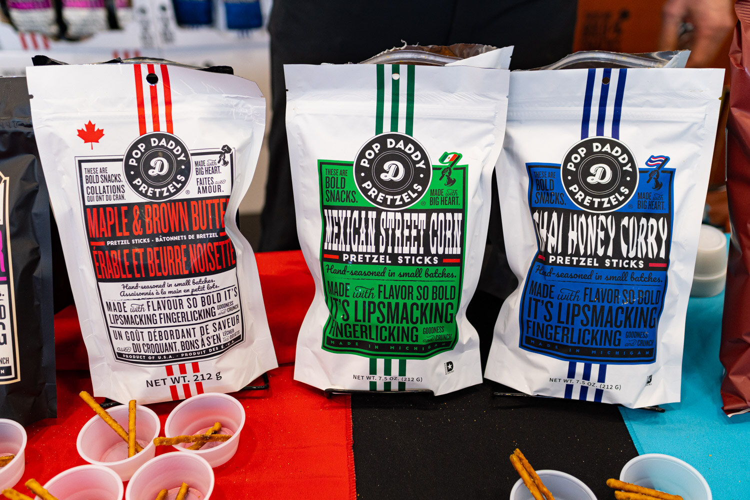 Bags of Pop Daddy pretzel sticks in several flavors with sample cups
