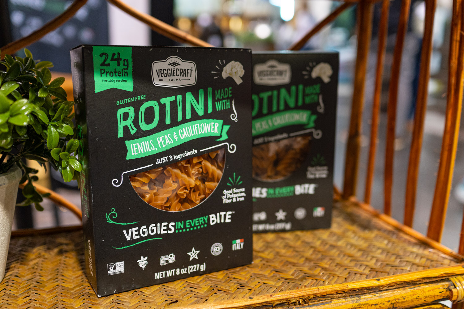 A Veggiecraft box of rotini lentil pea and cauliflower pasta on a rattan shelf