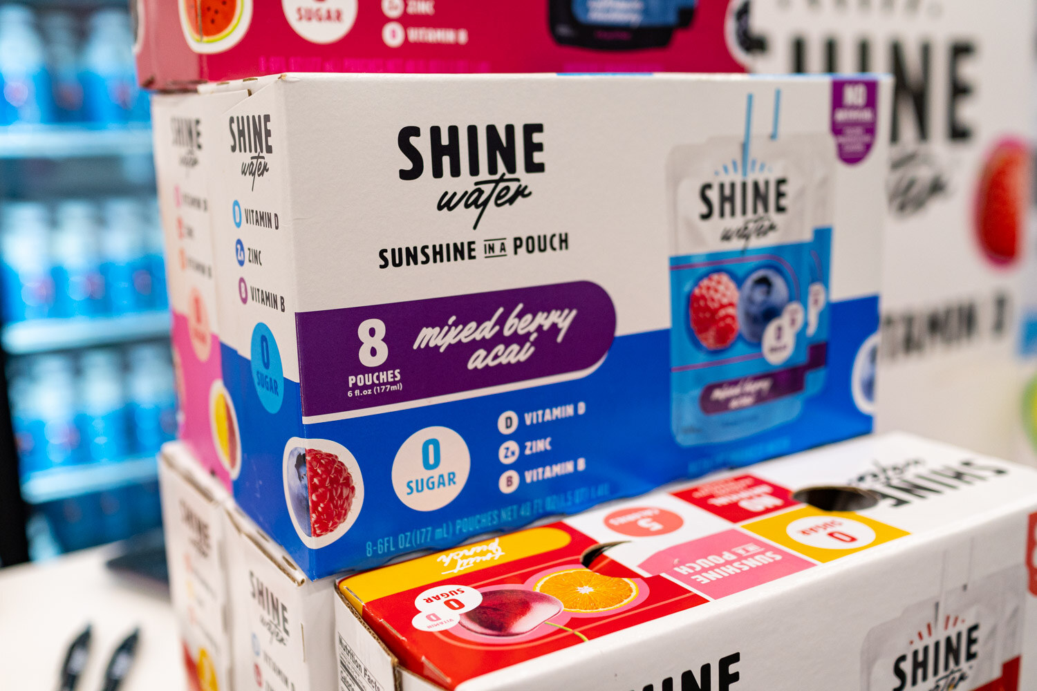 Stacked Shine Water boxes of mixed berry acai pouches