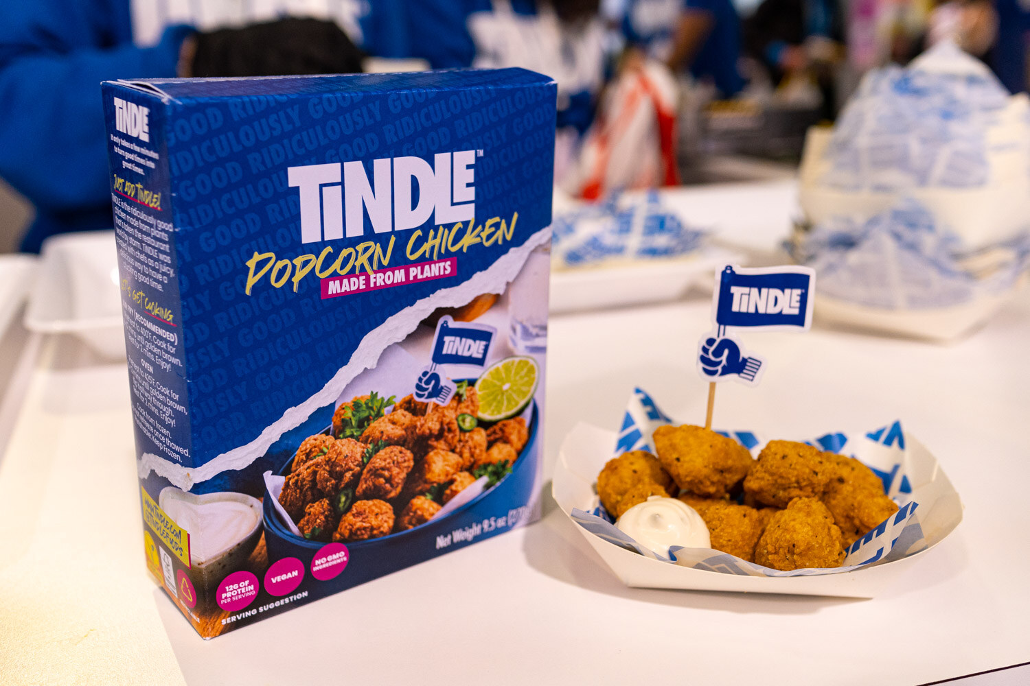A Tindle popcorn chicken box beside a paper boat of plant-based chicken nuggets