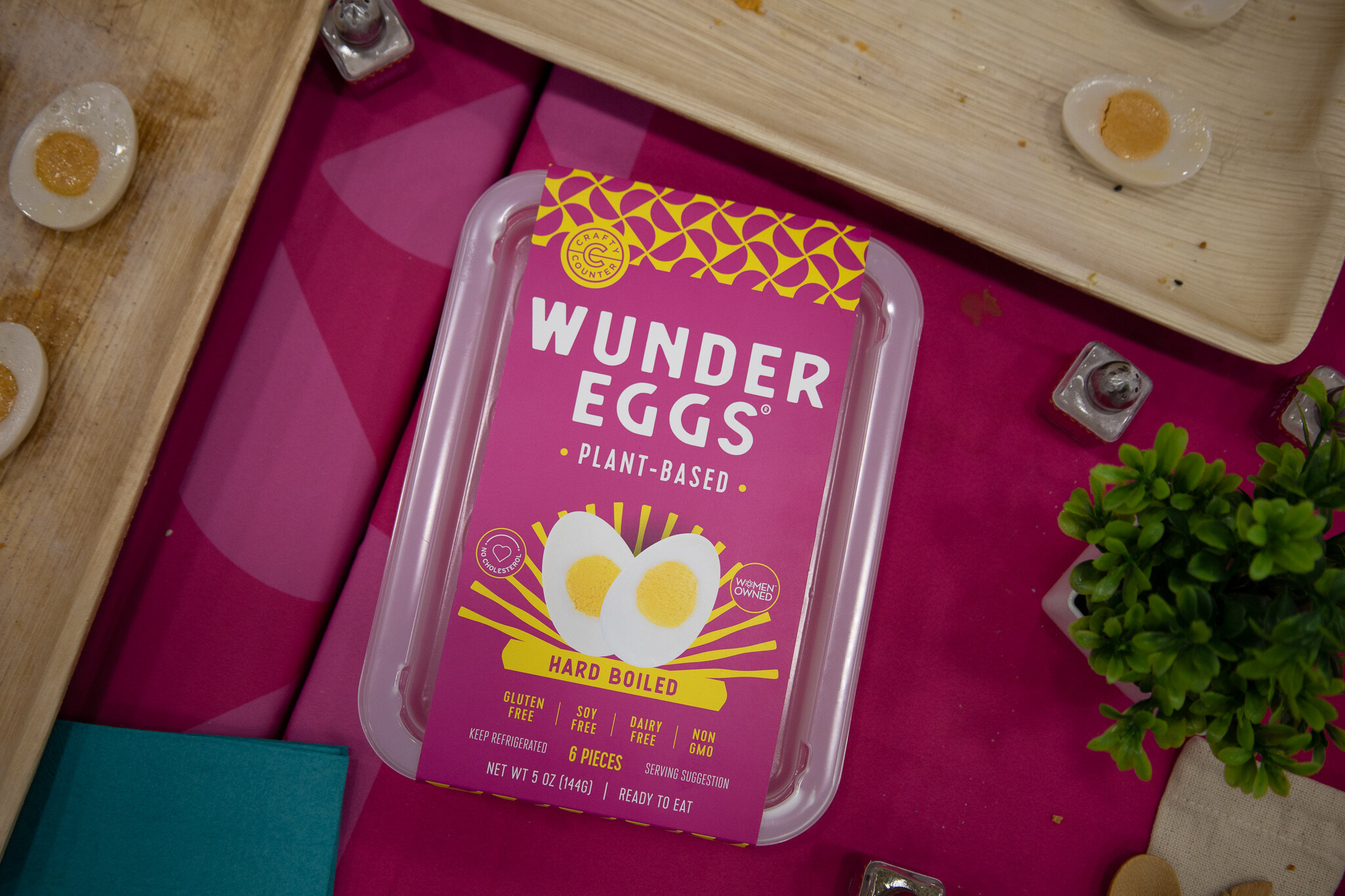 A tray of Wunder Eggs plant-based hard boiled eggs on a pink table with a halved egg nearby