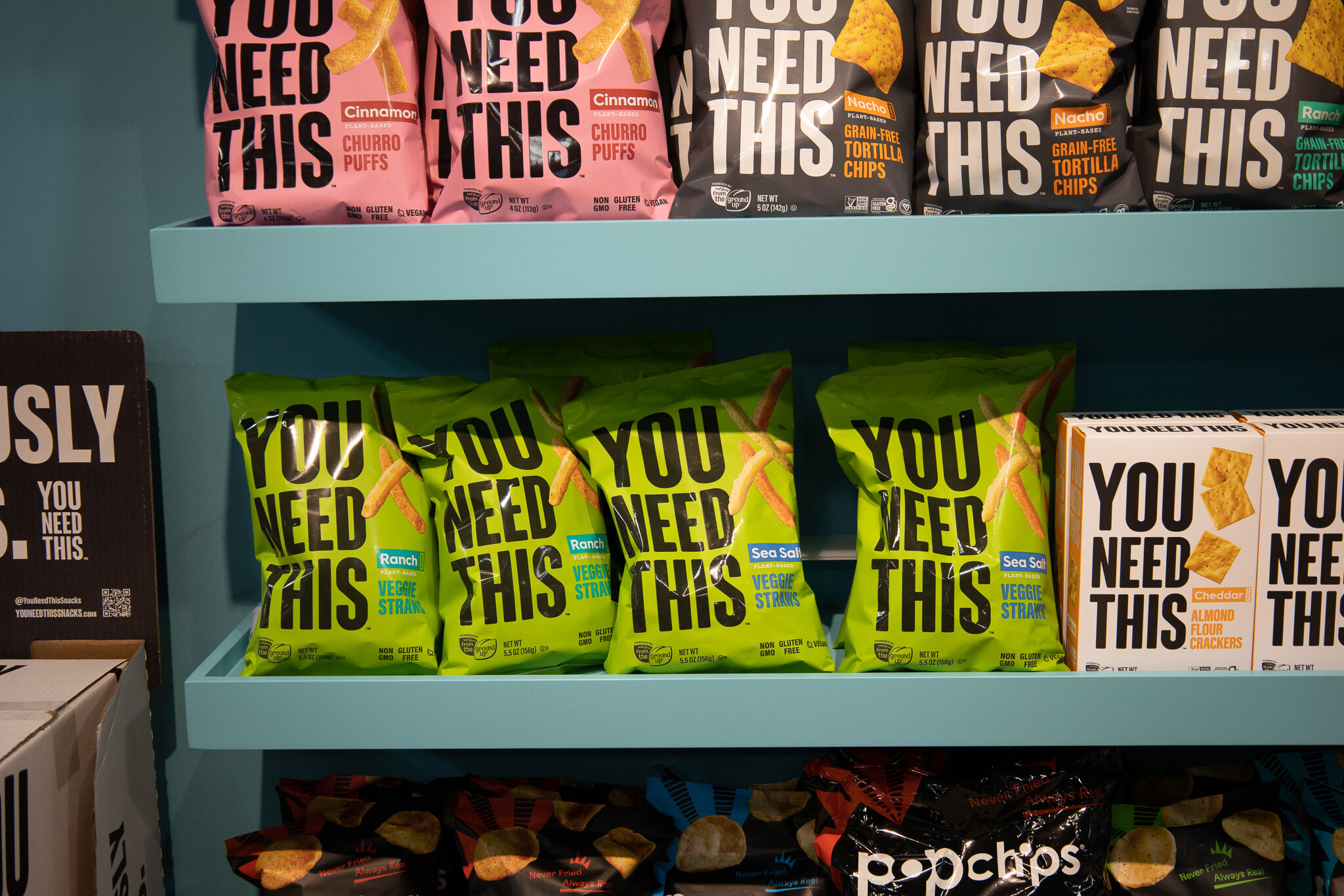 Shelves of You Need This chips and popchips bags on teal shelves