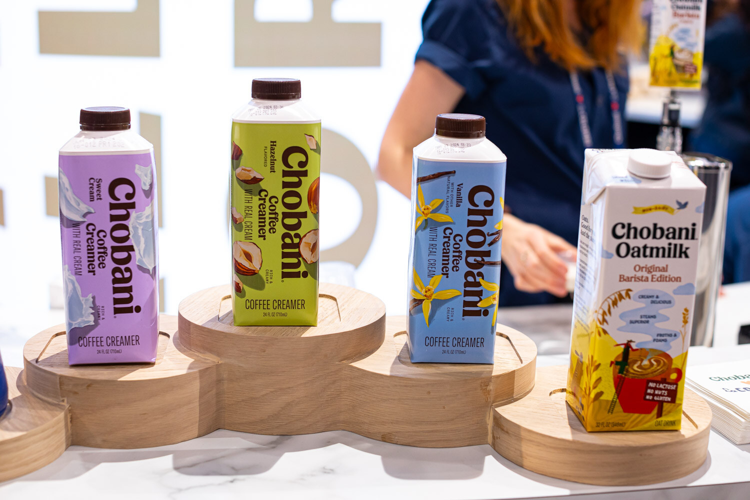Chobani coffee creamer cartons and an oatmilk carton on round wooden risers