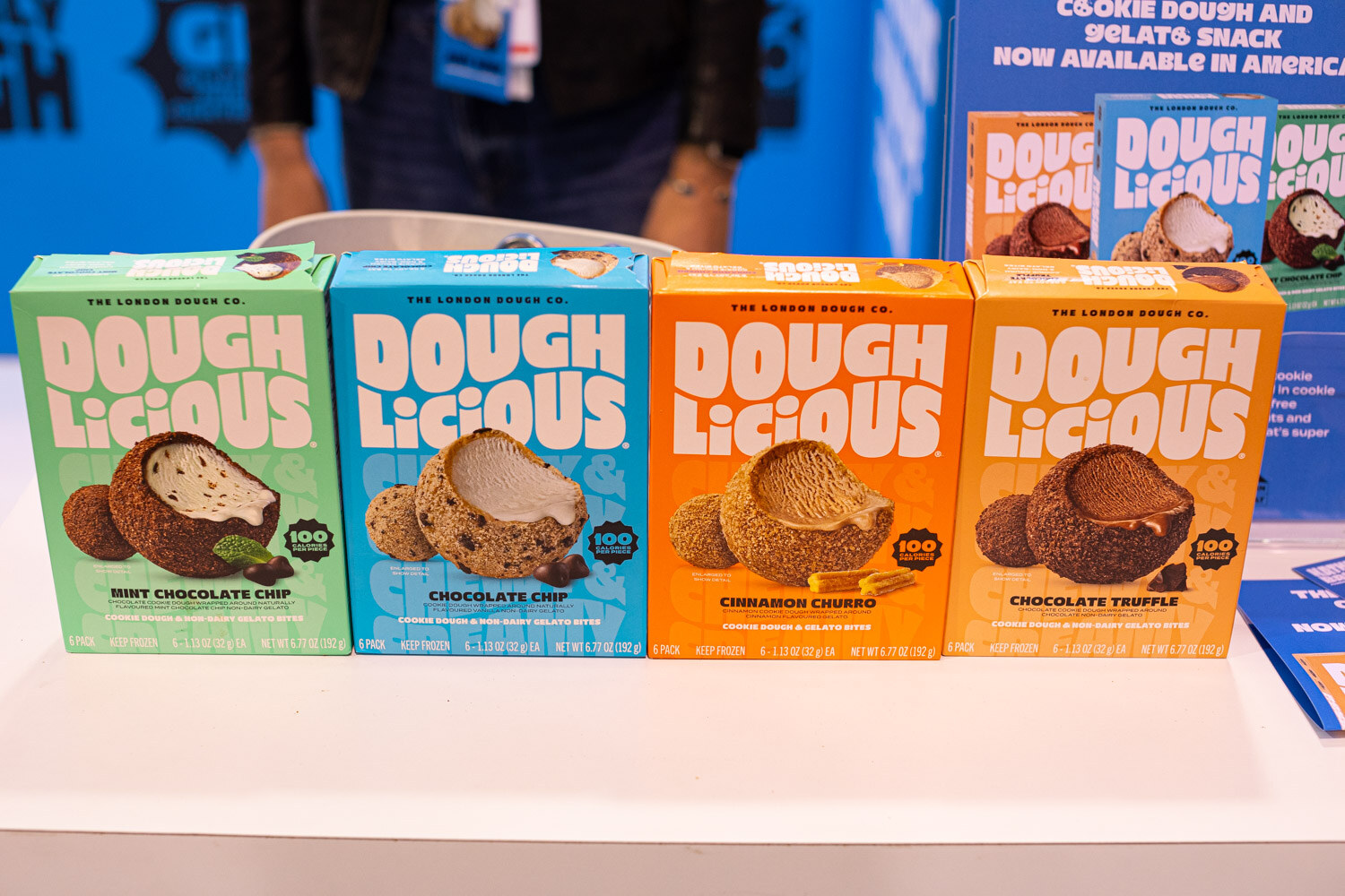 Four boxes of Dough Licious cookie dough in several flavors on a white counter