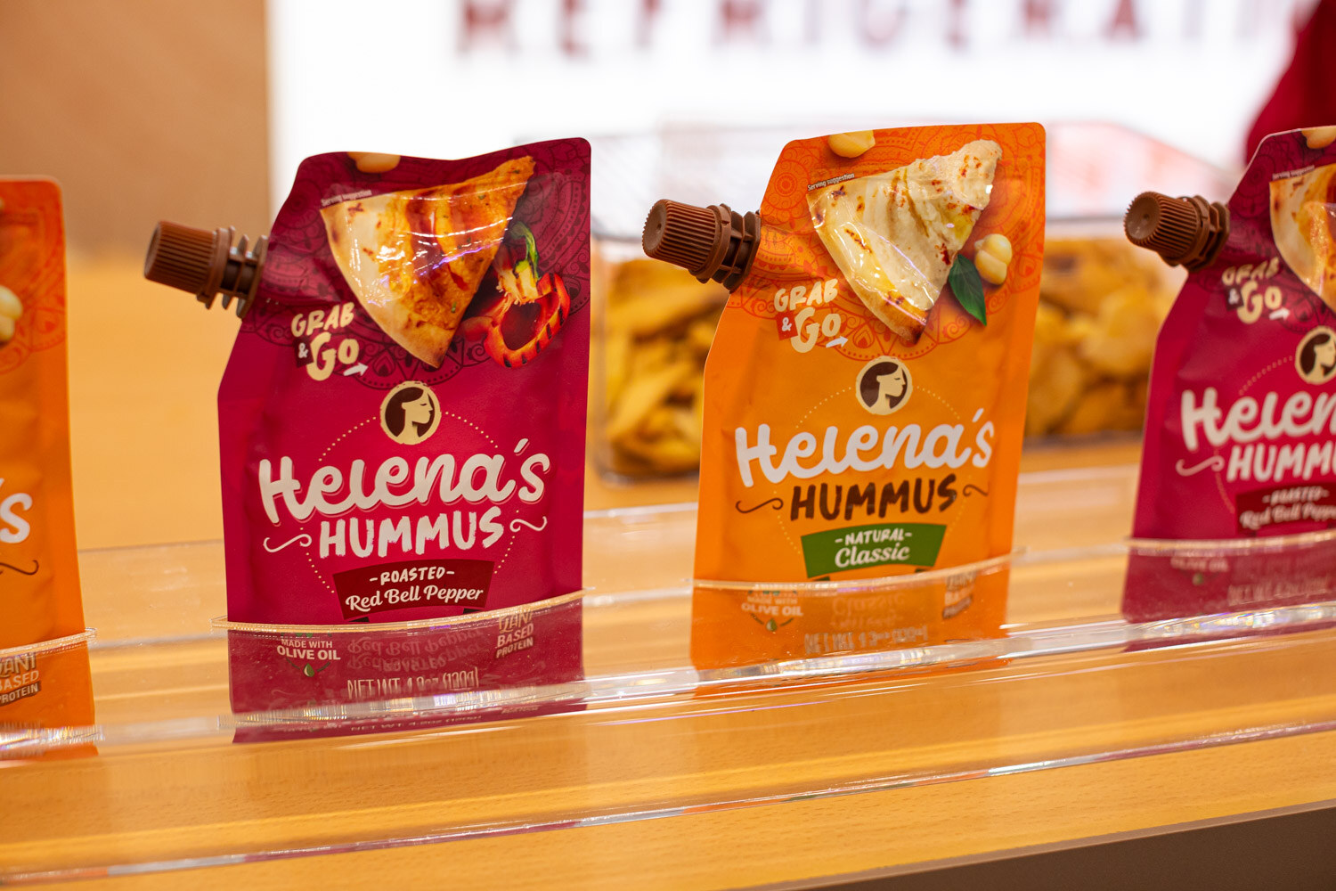 Helena's hummus squeeze pouches in red bell pepper and natural flavors on a clear display