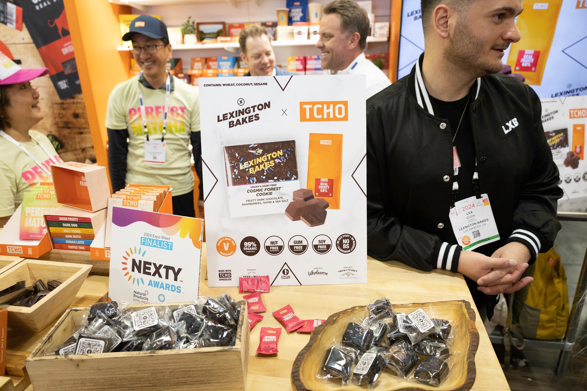 A booth with Lexington Bakes cookies and a Nexty Awards Finalist sign with several people smiling behind the counter