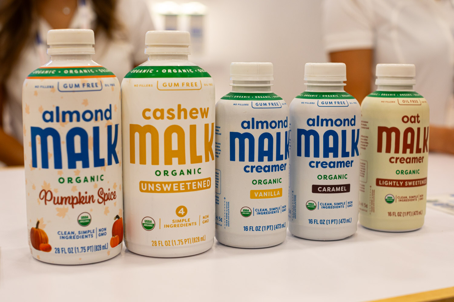 A lineup of Malk organic almond, cashew and oat milk bottles on a white table