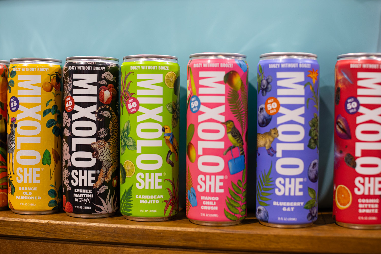 A row of colorful Mixolo She cans along a wooden shelf