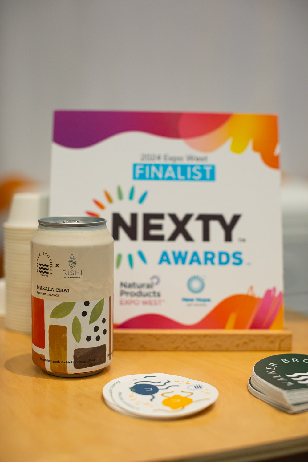 A Nexty Awards Finalist 2024 Expo West sign next to a beverage can and coaster on a table