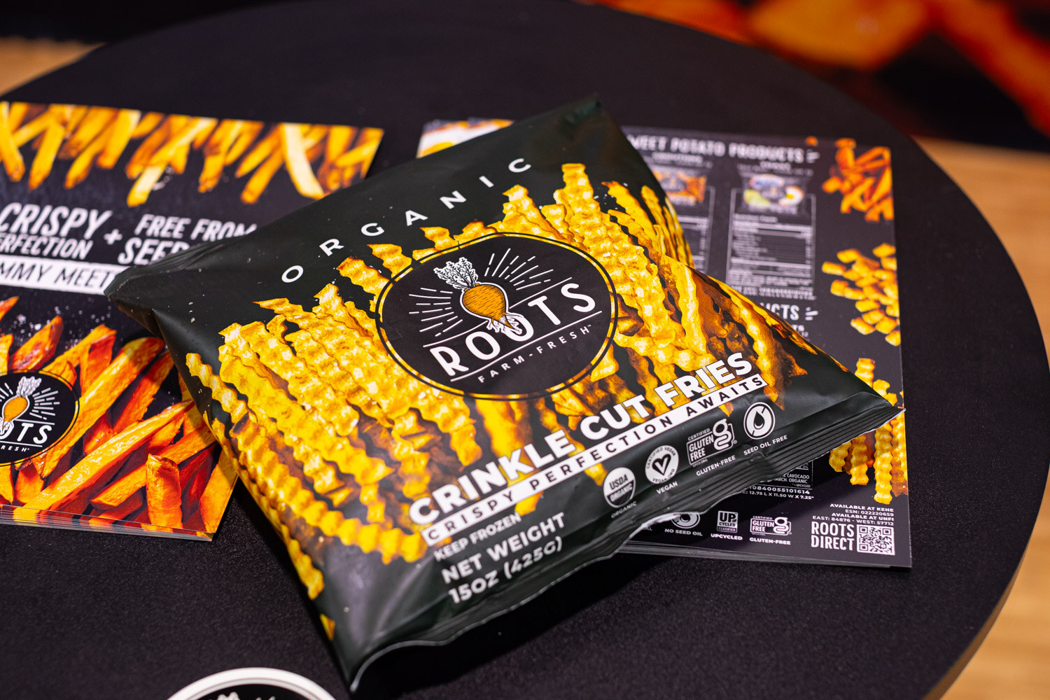 A bag of Roots Farm Fresh organic crinkle cut fries on a round black table