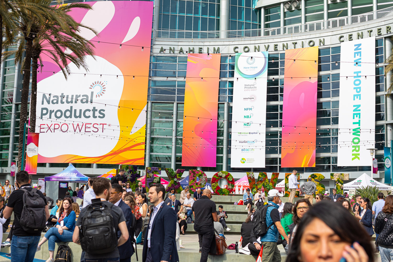 The Anaheim Convention Center with large Natural Products Expo West banners above a crowd of attendees